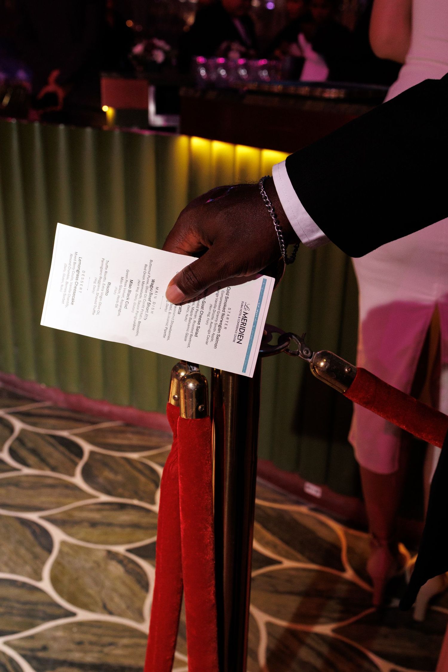 Close-up of hands holding program materials against a patterned floor background.