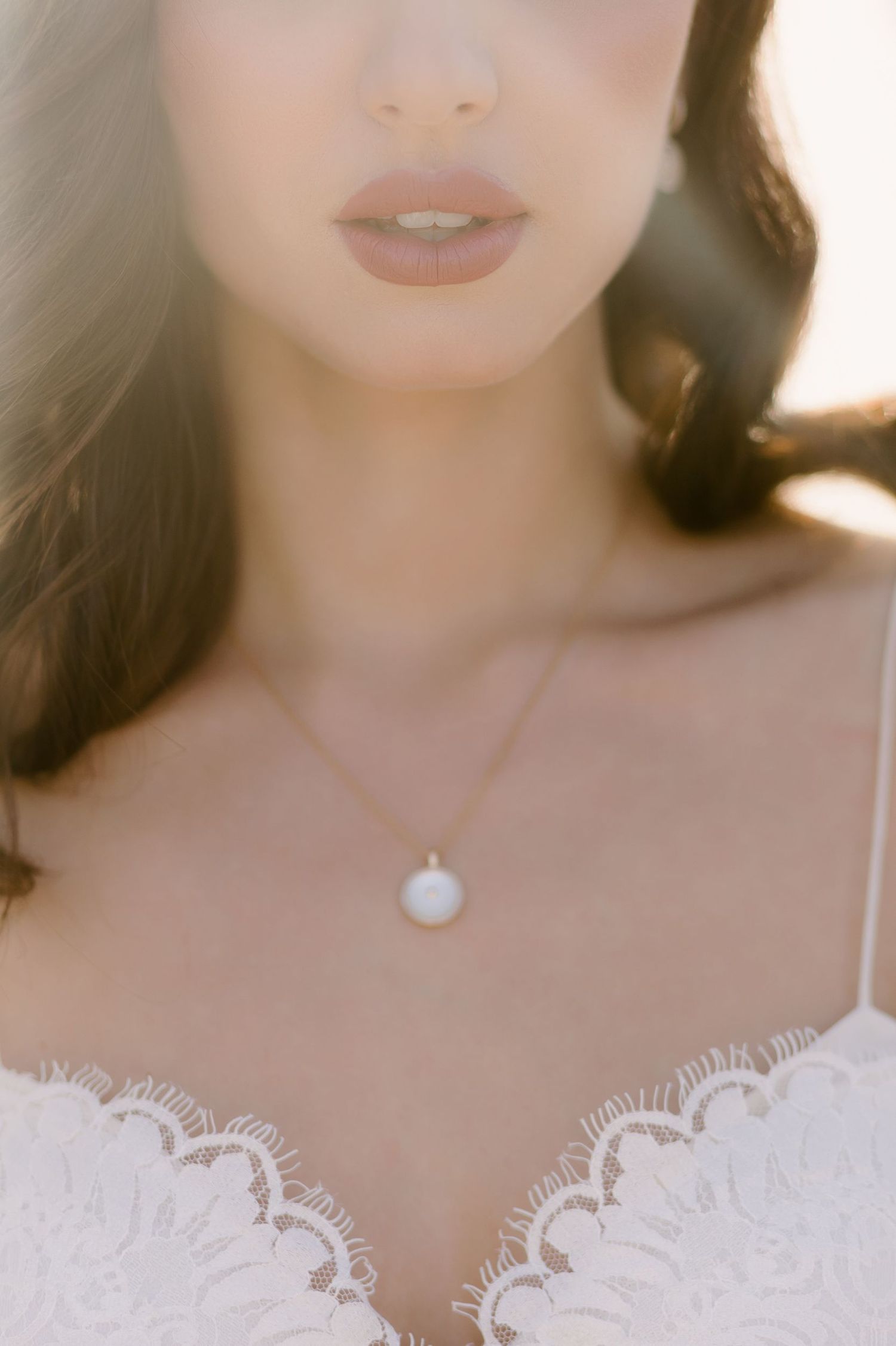 Close-up detail of delicate lace trim and pearl necklace on bridal attire.
