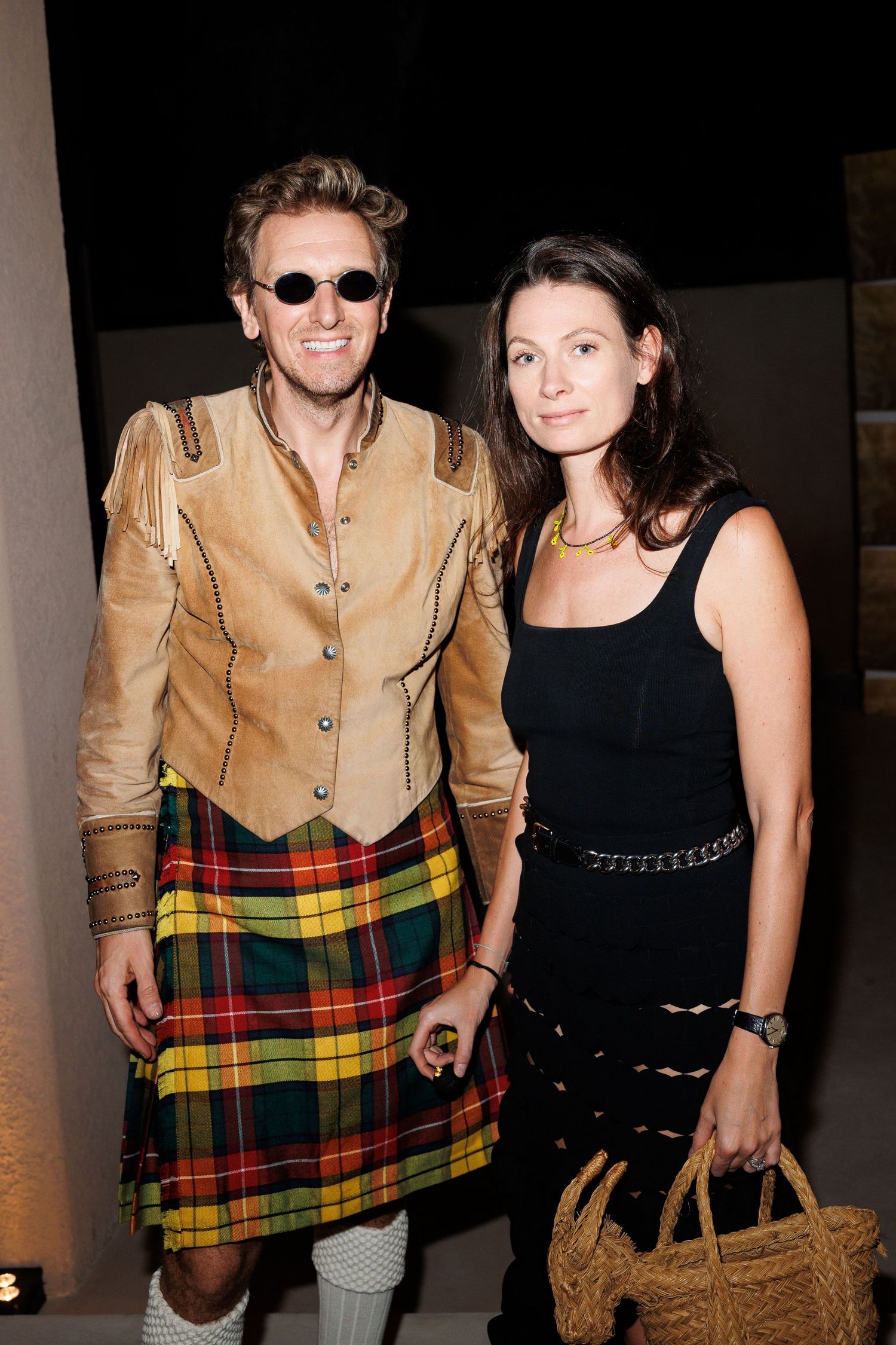 Two people pose together, one wearing a traditional Scottish kilt and tan jacket.