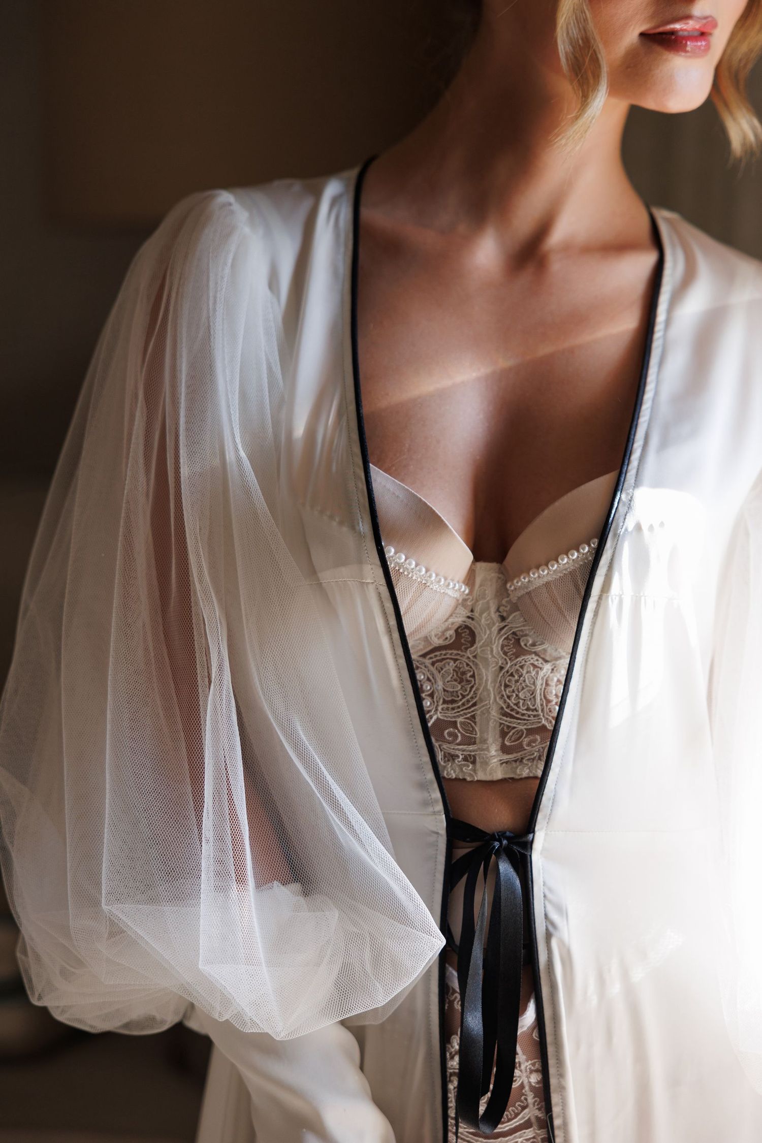 Close-up details of white lace robe and lingerie in romantic boudoir setting.