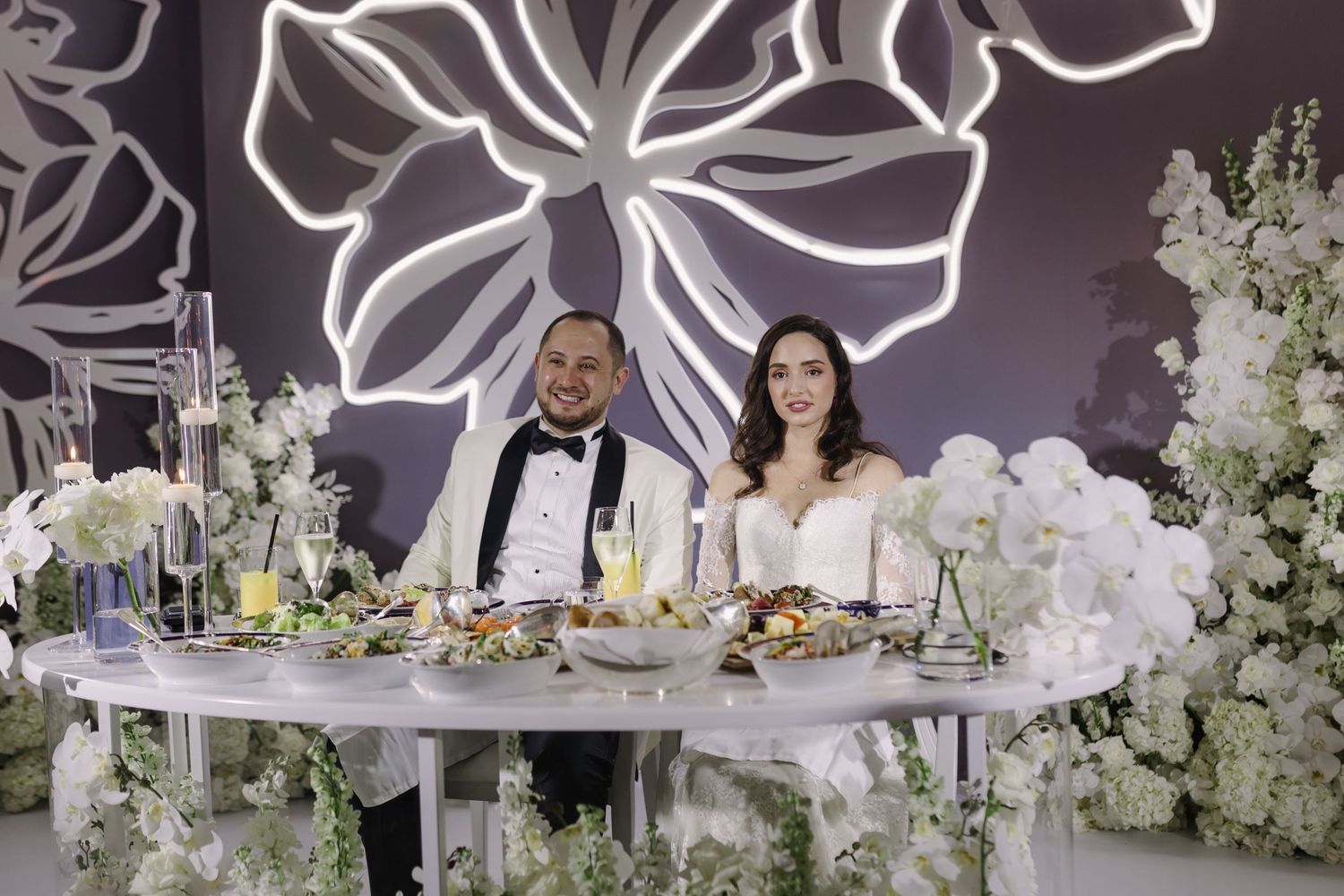 Wedding reception decor featuring large floral centerpieces and elegant white table settings.