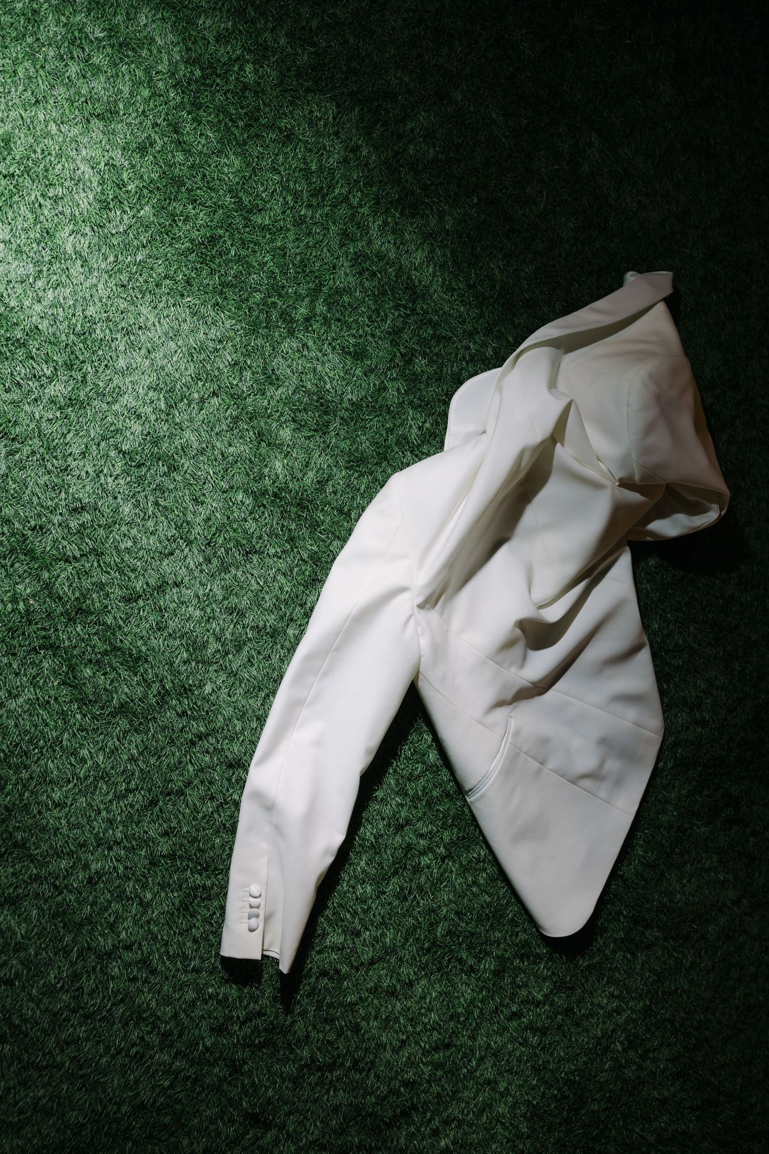 White formal clothing laid out on dark green carpet in dramatic lighting.