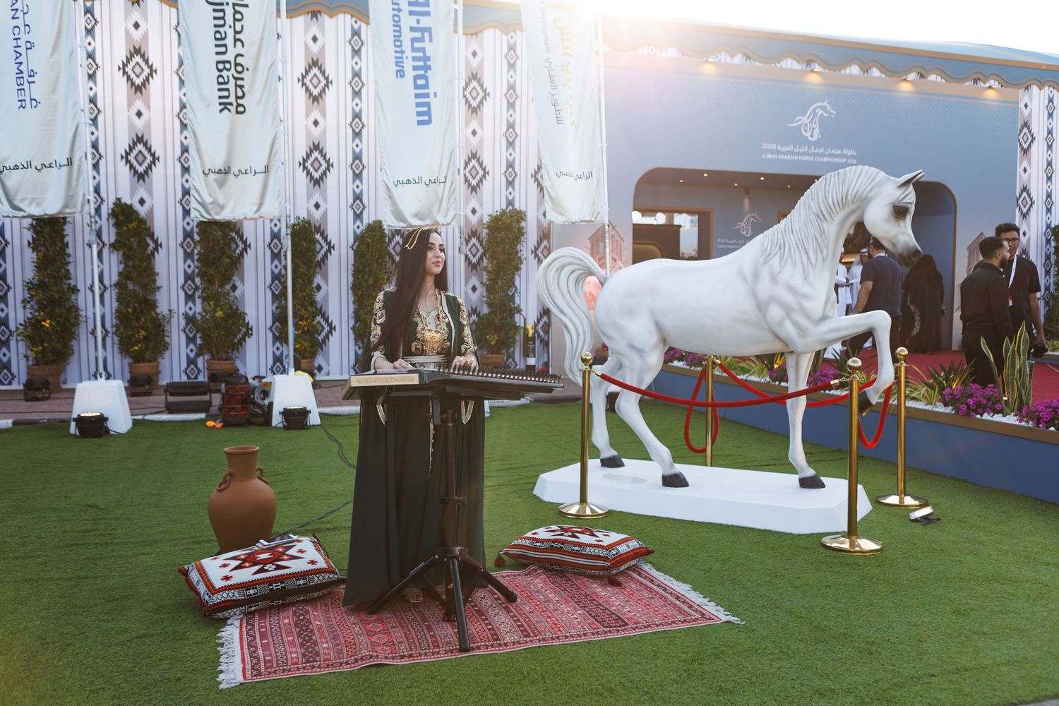 A white horse statue displayed on artificial grass with decorative pillars and event setup in the background.
