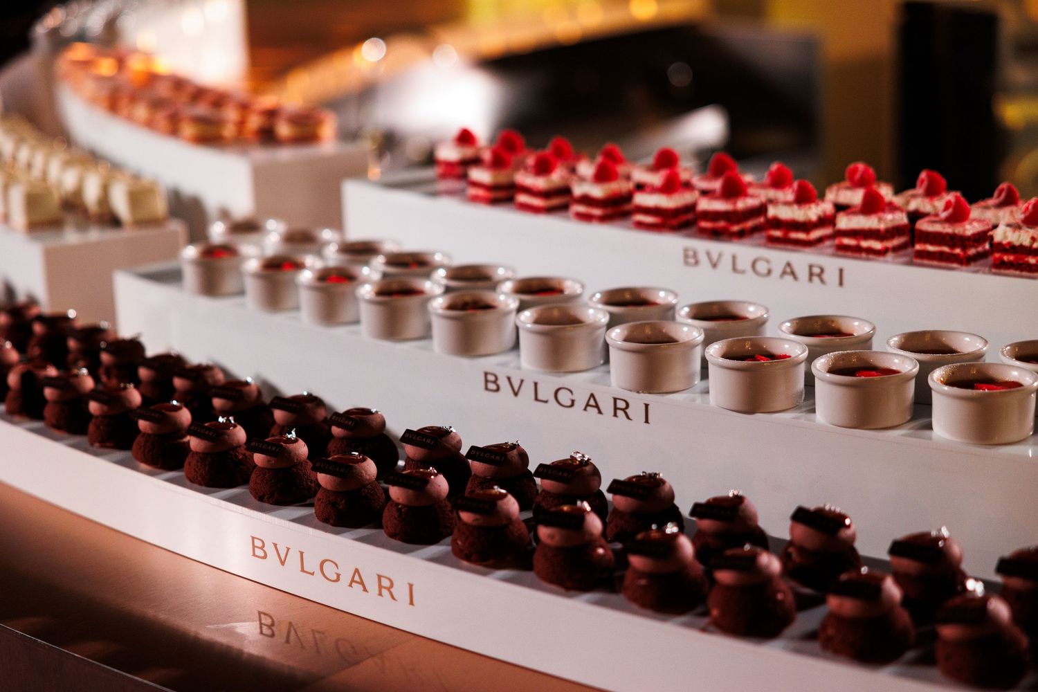 Rows of elegant Bvlgari chocolate truffles displayed on a luxurious serving platter at a high-end event.