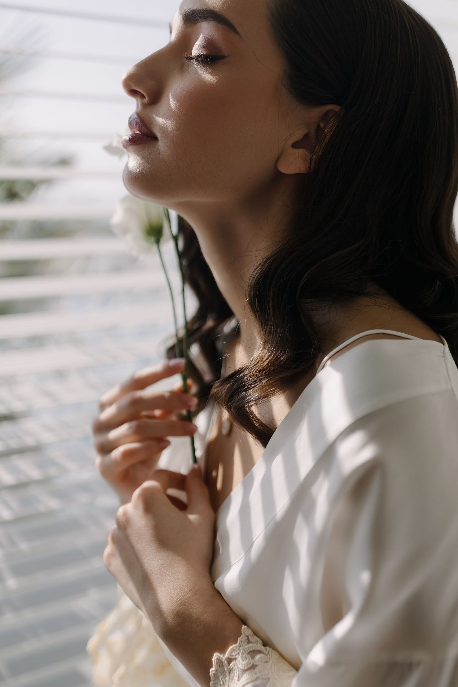 Side profile shot near window with soft natural lighting and floral elements.