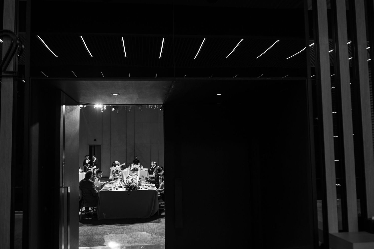 Dramatic black and white view through doorway into dimly lit reception space.