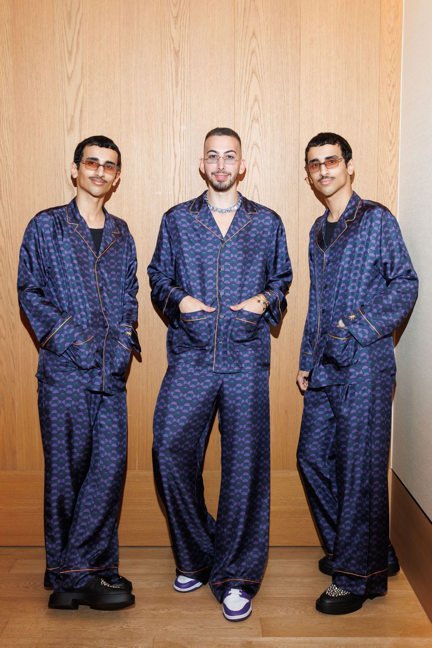 Models lined up wearing coordinated navy blue patterned loungewear against wooden wall.