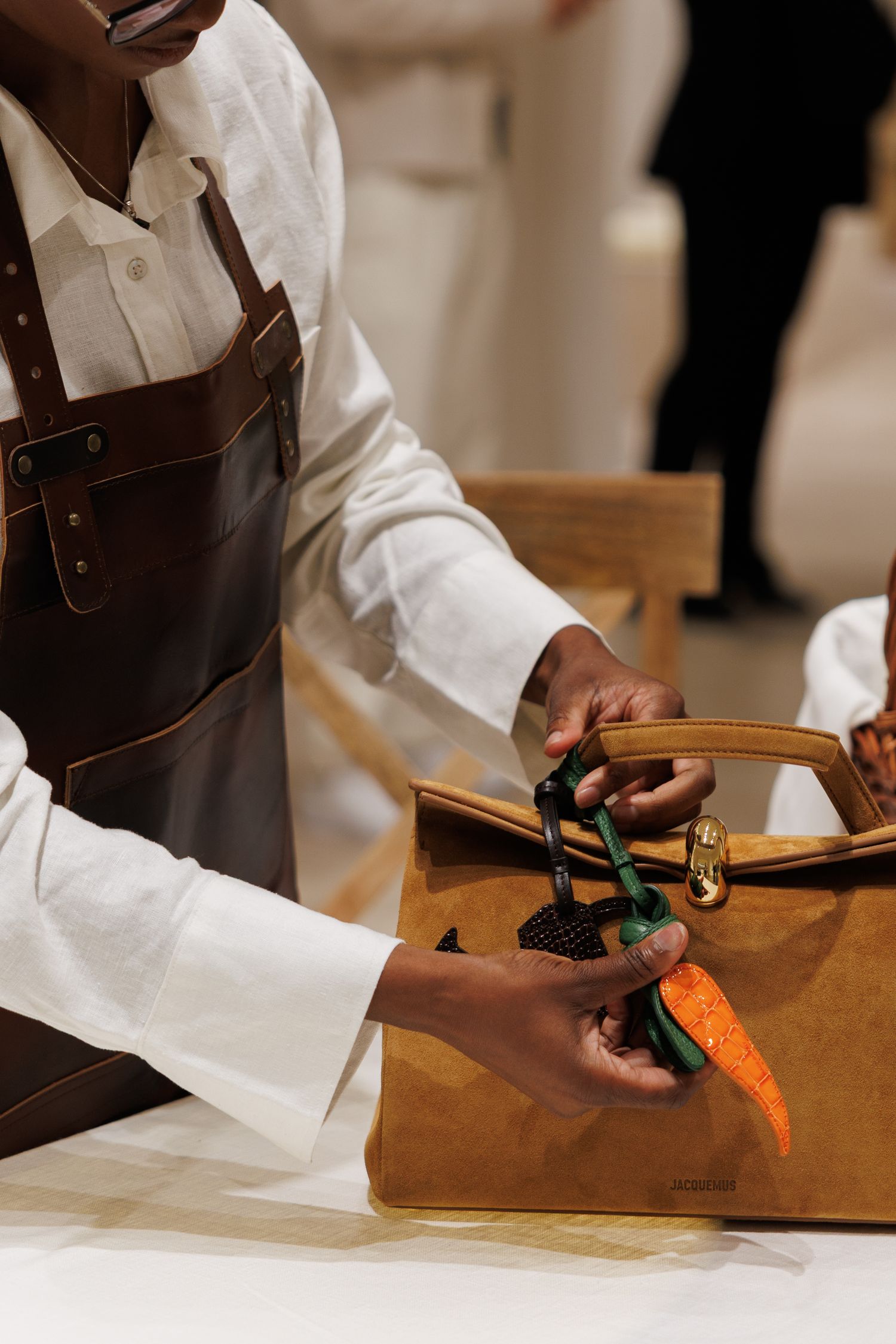 Close-up of hands working with leather materials and tools on a wooden surface.