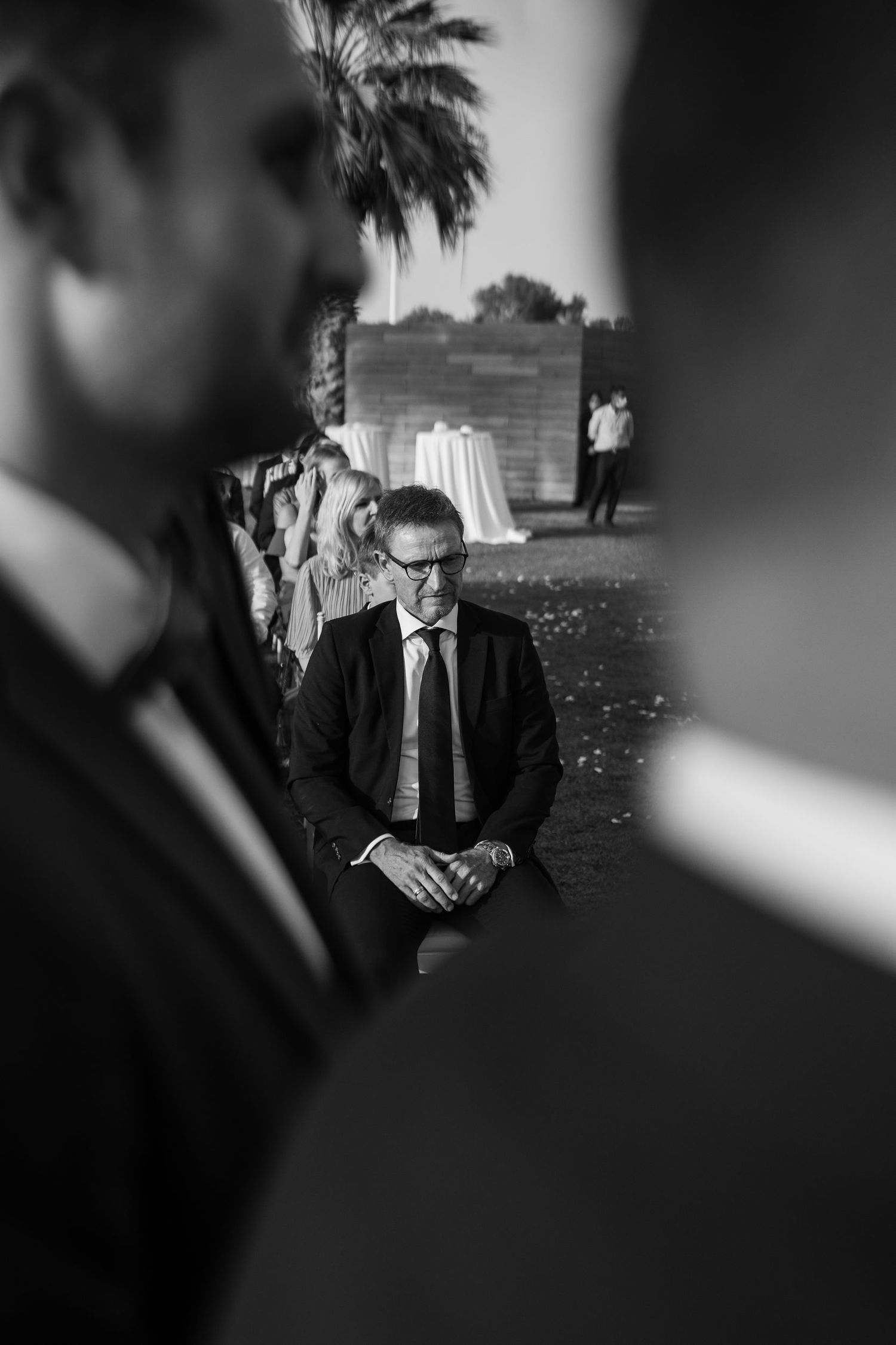 Atmospheric black and white portrait of wedding guests at outdoor venue.
