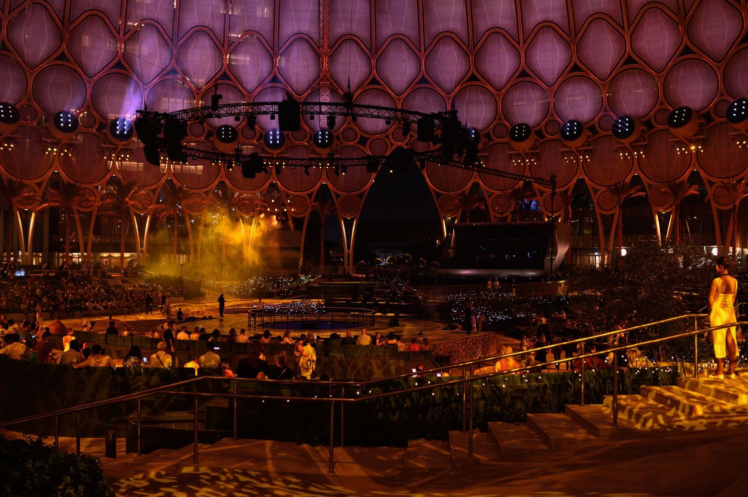 Illuminated geometric dome structure glows with warm lighting at night.