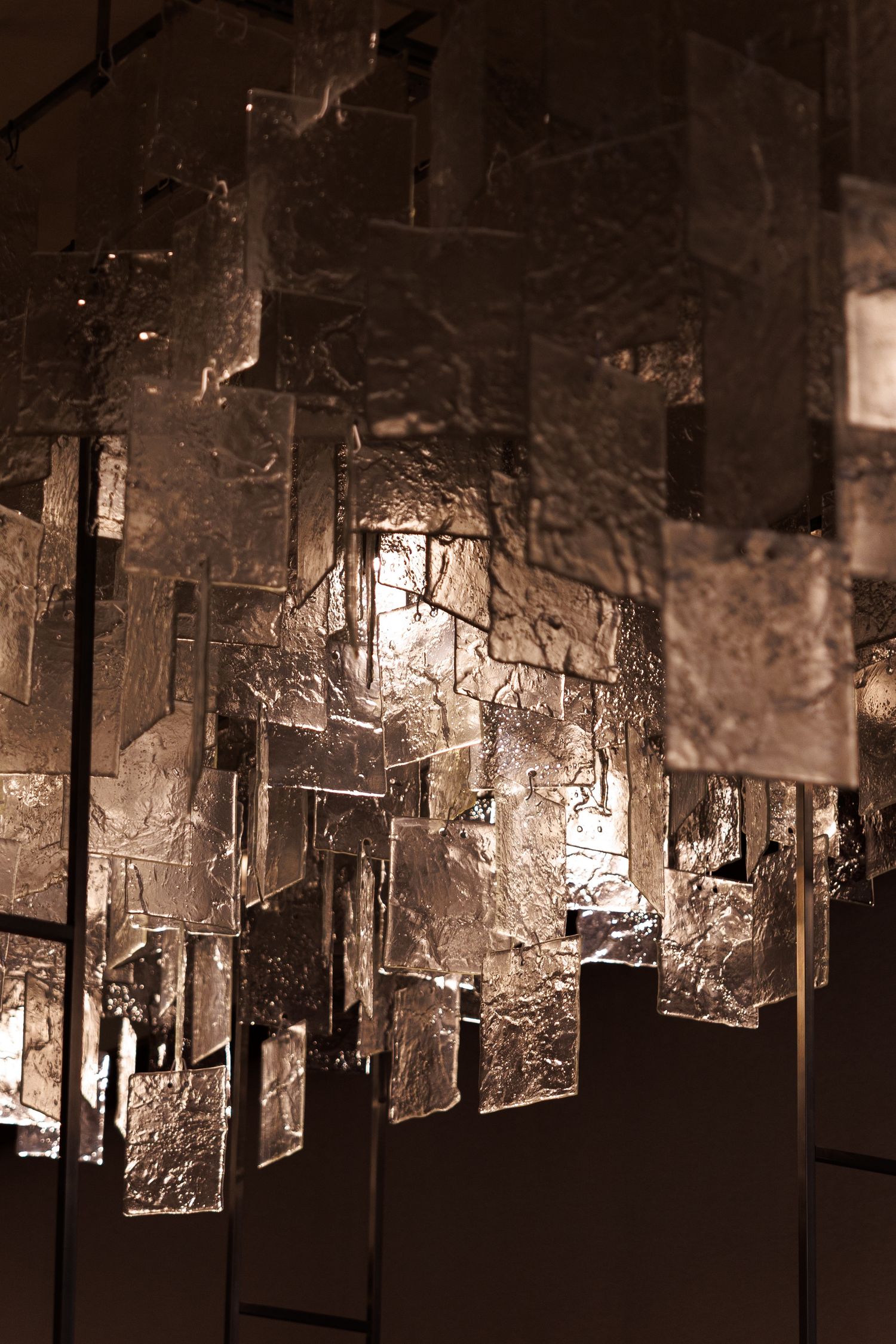 Abstract art installation with hanging glass panels creating a geometric light pattern.