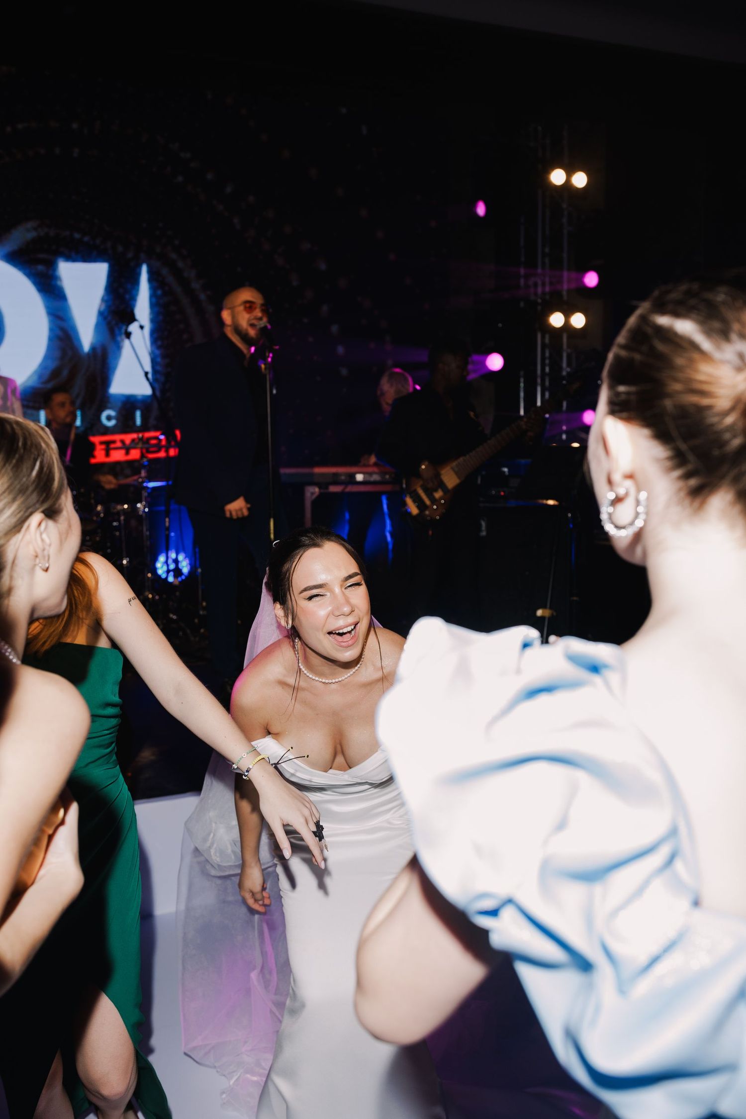 Energetic wedding reception dance party with colorful lighting effects.