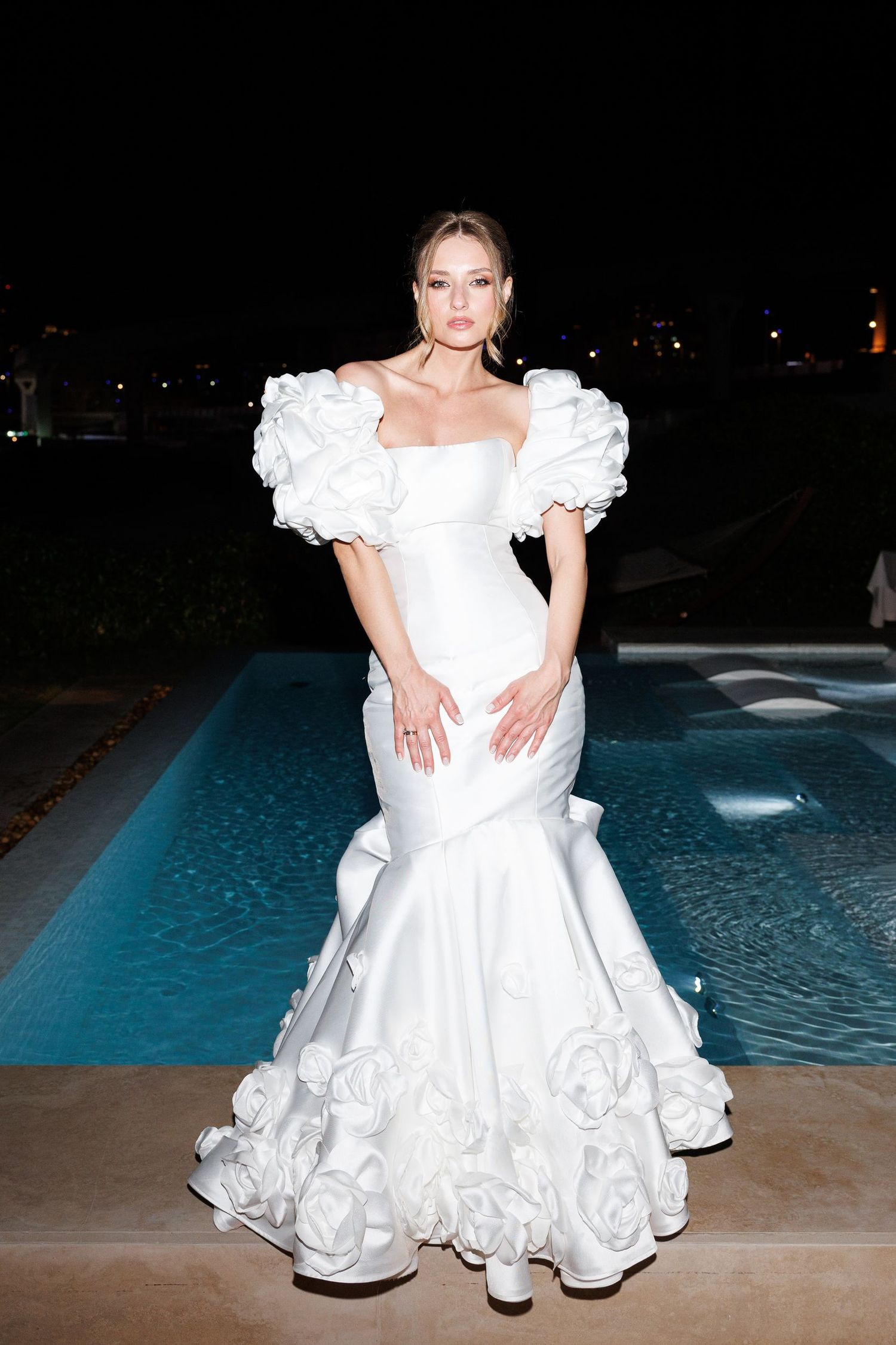 White wedding dress with ruffled details photographed poolside at night.