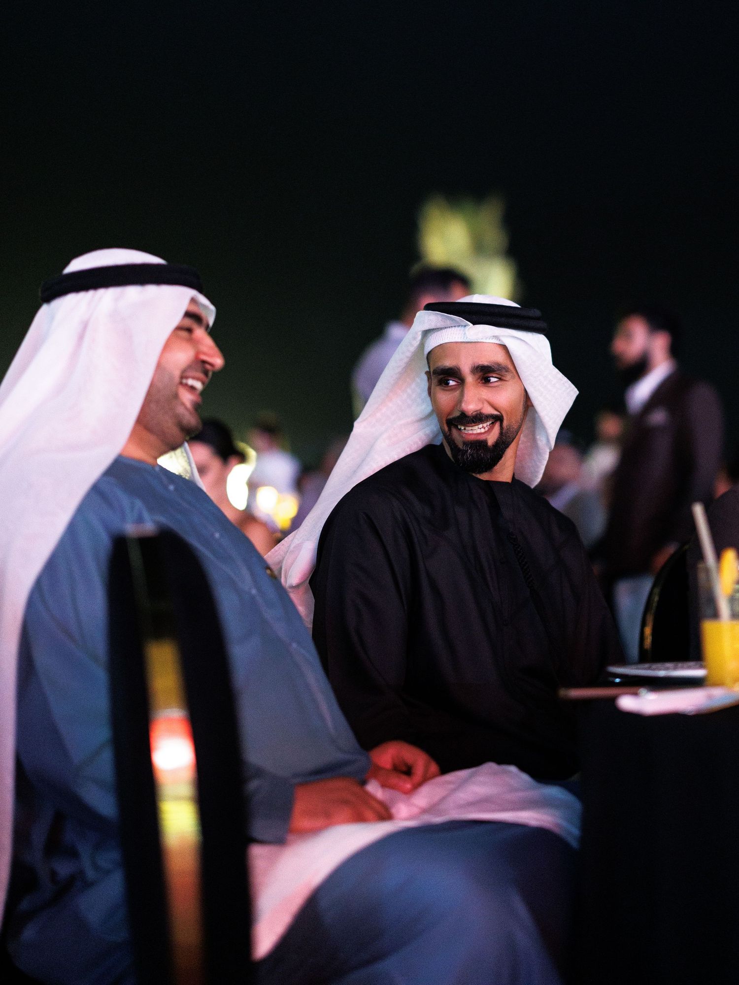 Men in traditional Middle Eastern dress gather and interact at a formal event.