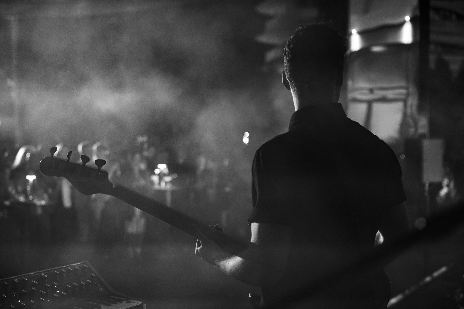 Silhouette of a musician performing on stage with a guitar in a smoky, dimly lit venue.