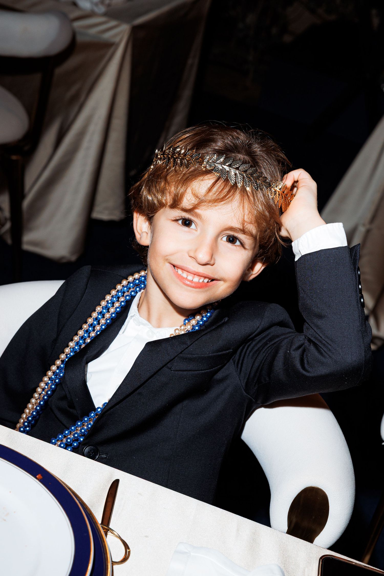 A child wearing a navy blazer and white shirt poses playfully in a series of candid shots.