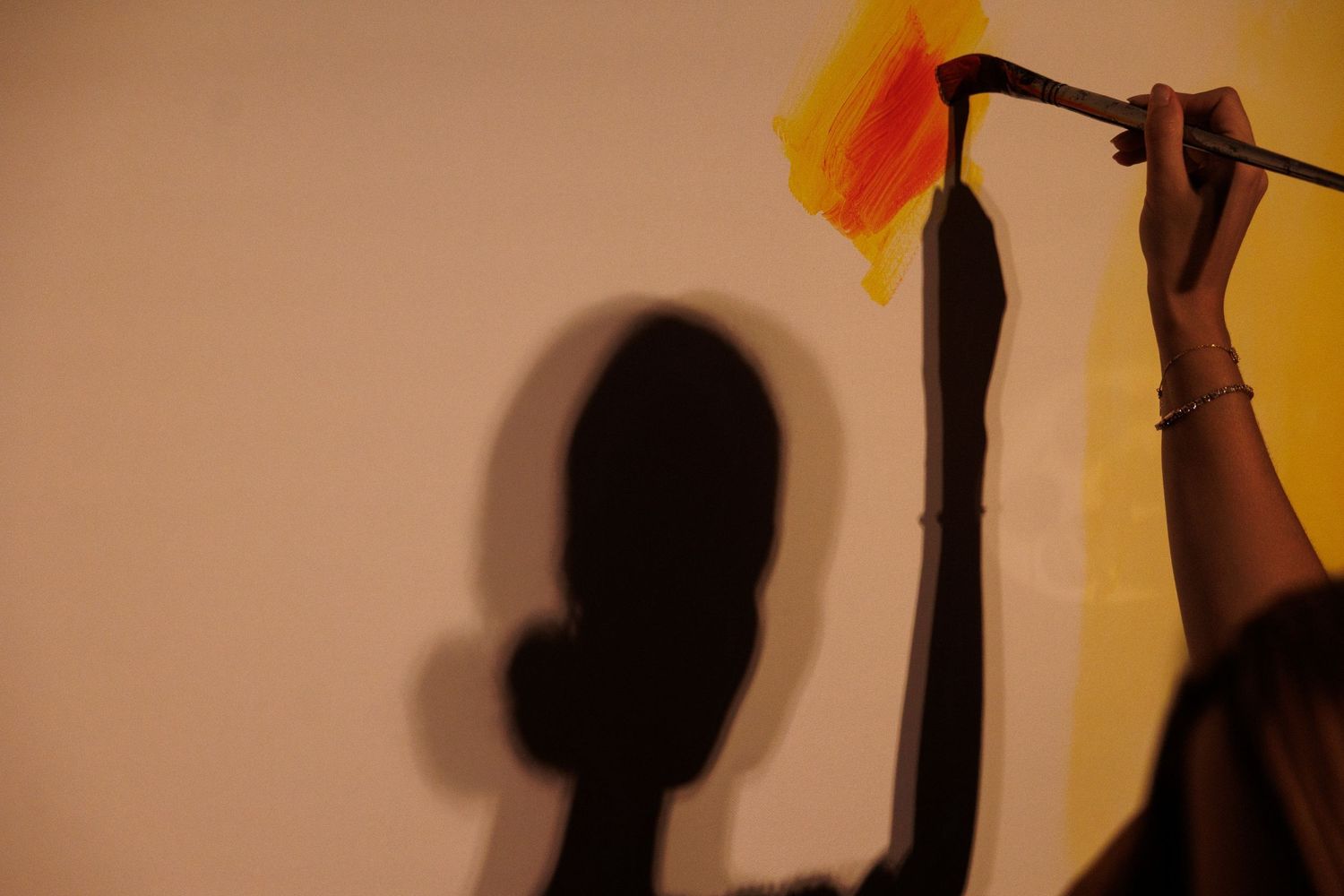 Shadow silhouettes cast on warm-toned wall in artistic composition.