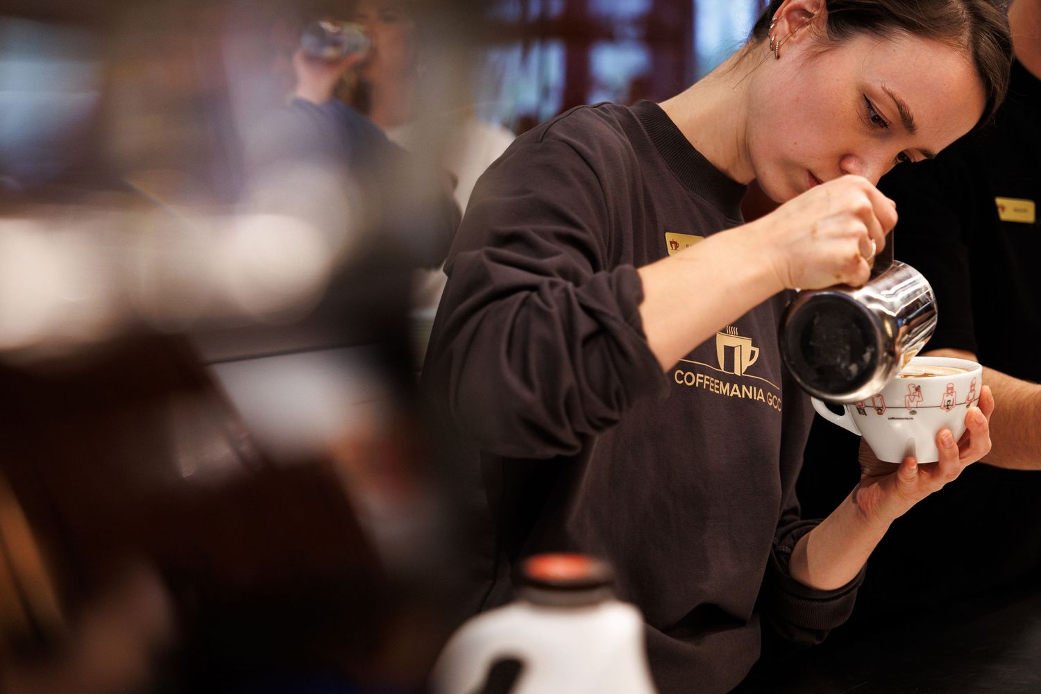 Person drinking from coffee cup in warm-toned cafe lighting.