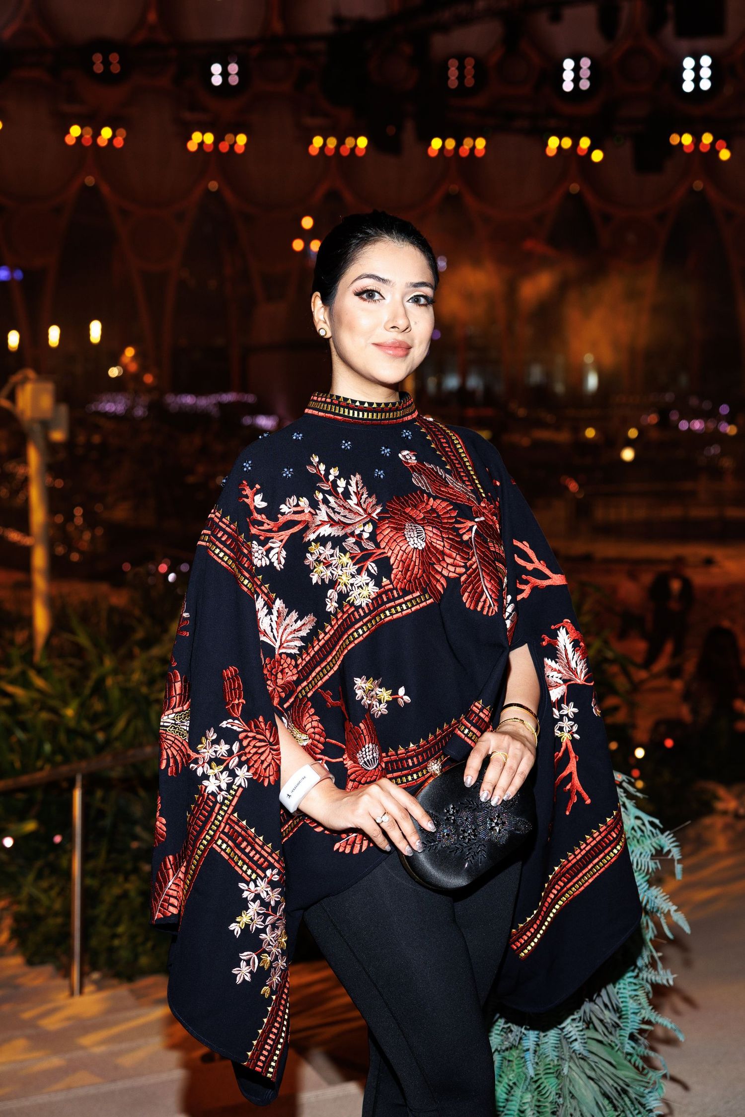Person wearing black floral kimono-style garment poses against evening backdrop.