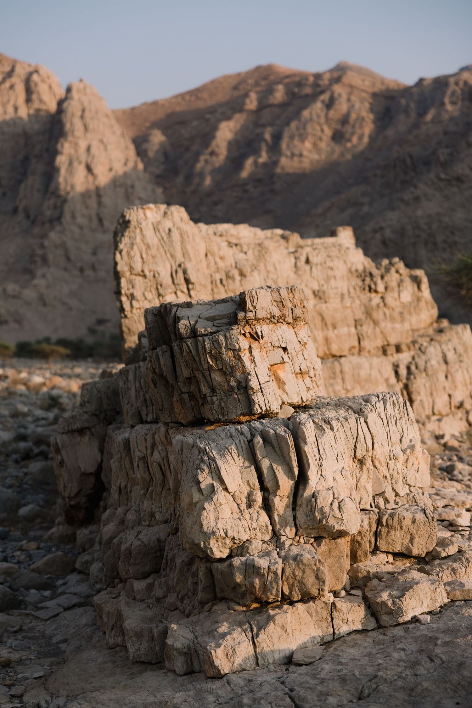 Layered rock formations in a desert mountain landscape during golden hour.