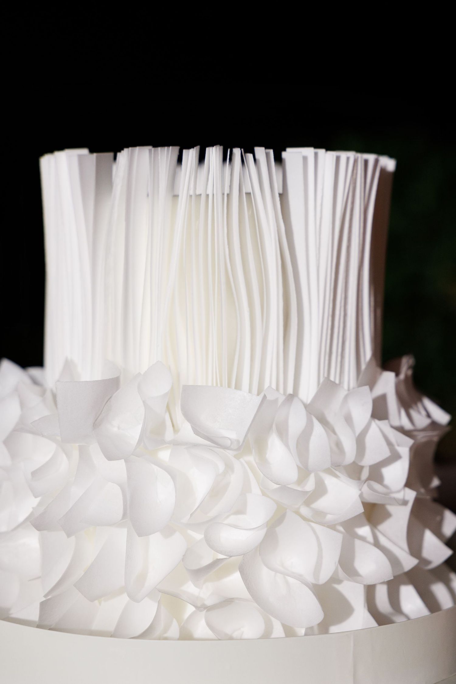 Close-up of an elegant white wedding cake with intricate ruffled texture details.