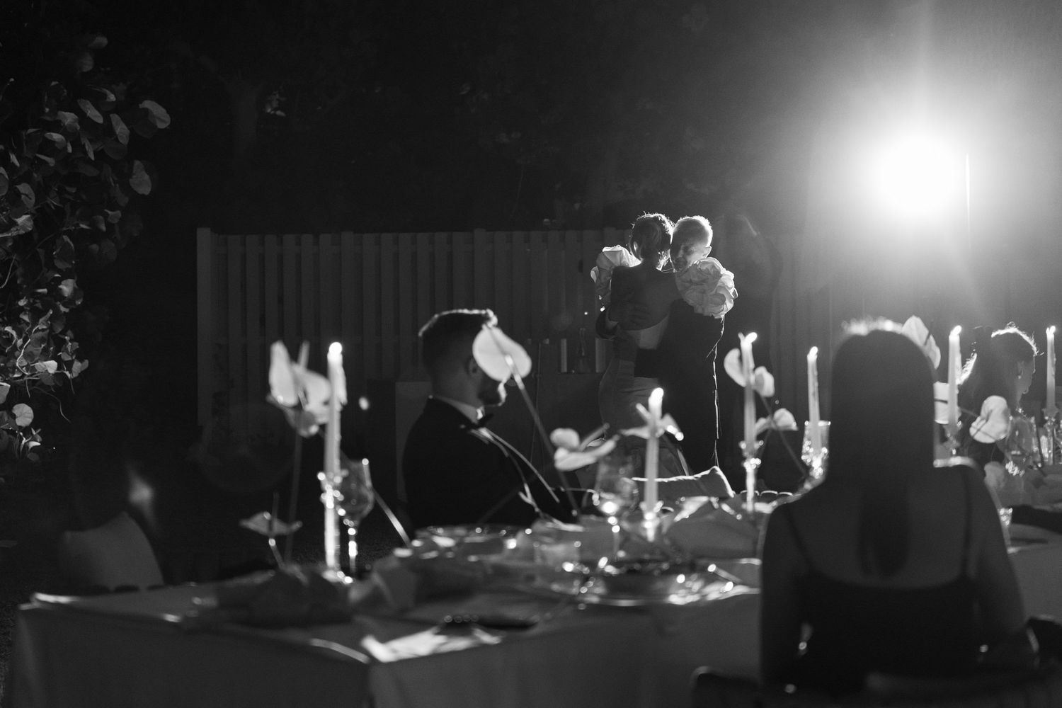 Wedding reception guests mingling under outdoor lighting at night.