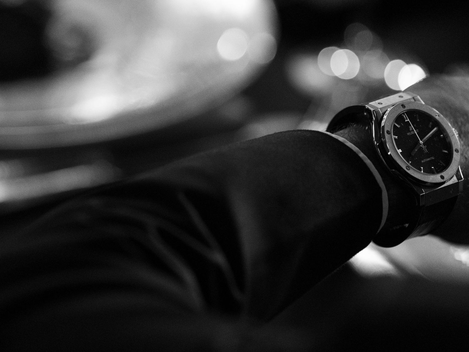 Close-up black and white photograph of a watch dial with blurred background.