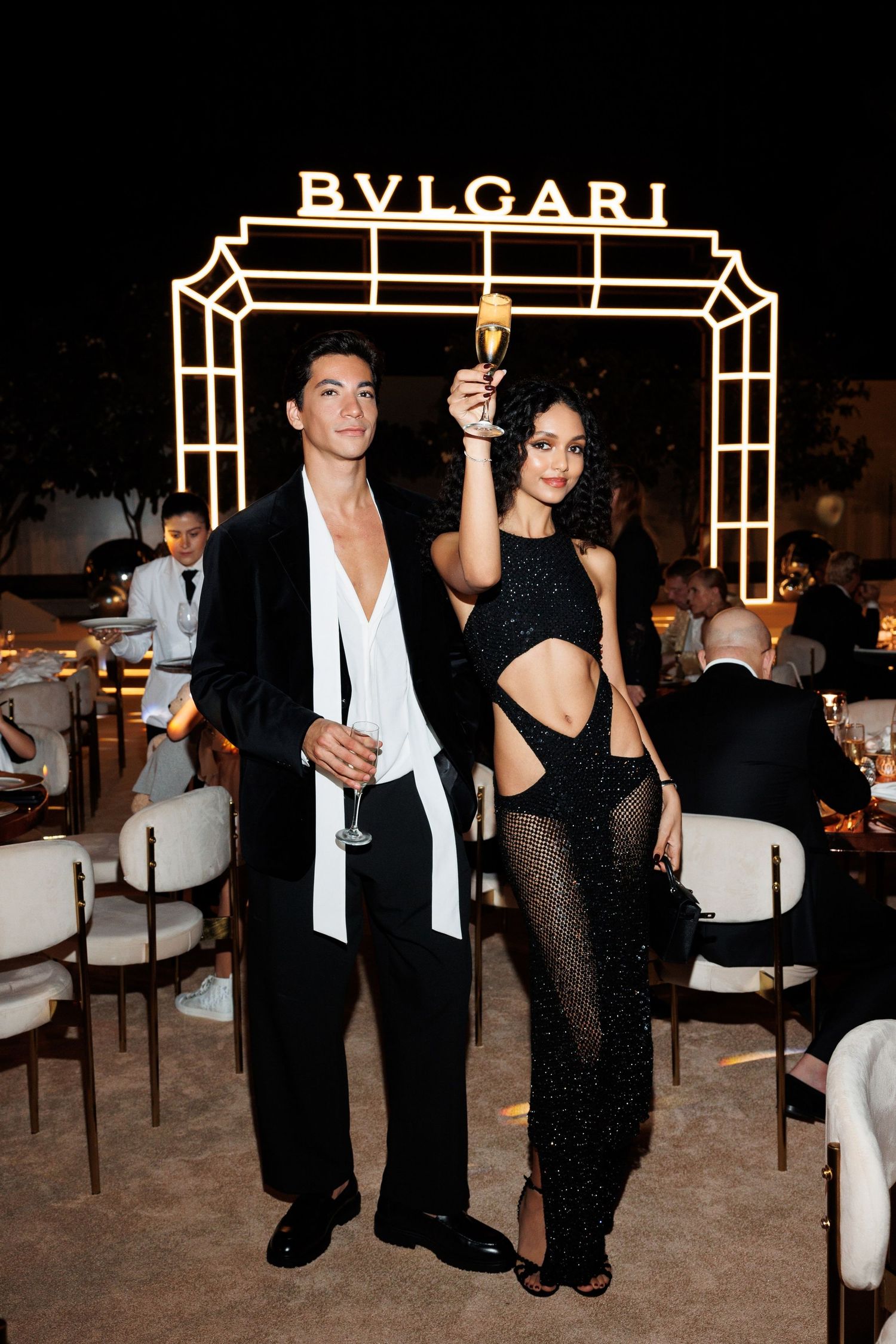 Elegant evening event at Bulgari with illuminated signage and formal attire.