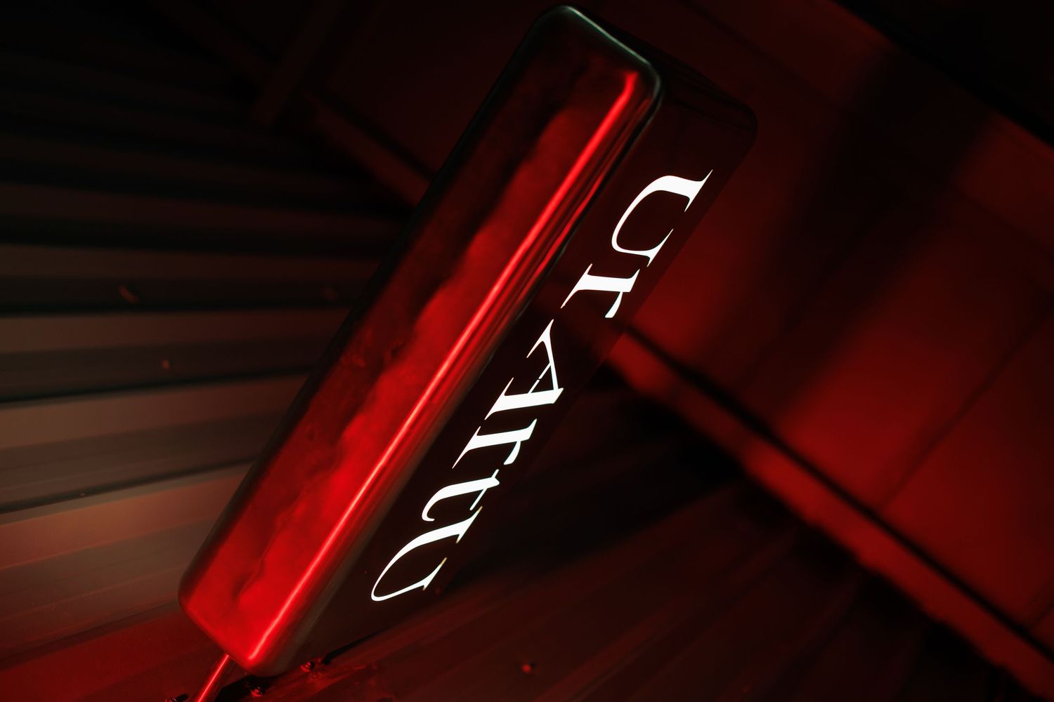 Red neon lights illuminate a dark corridor with geometric shapes and reflective surfaces creating a modern ambiance.