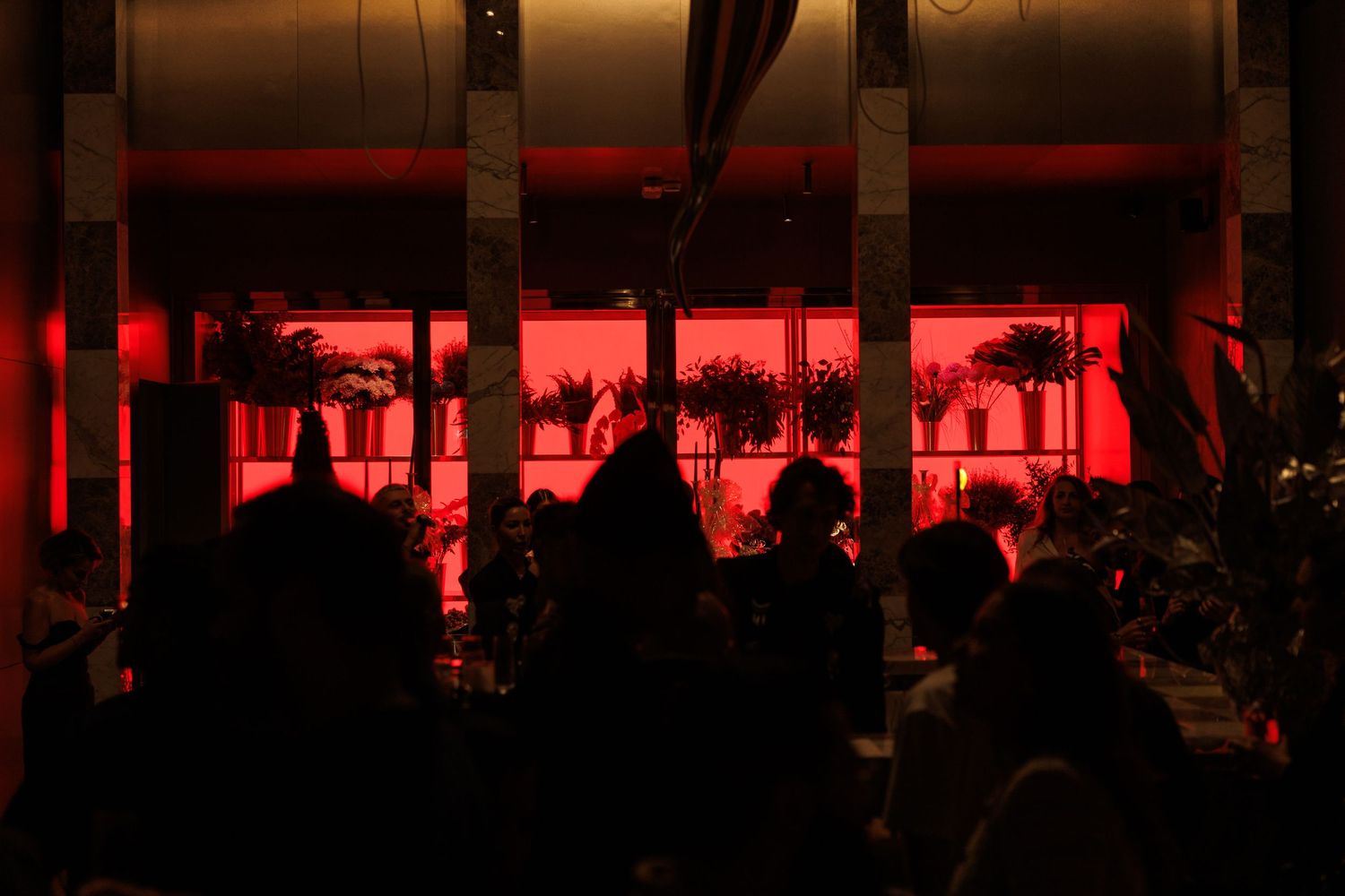 Concert venue silhouetted against dramatic red lighting with crowd visible in dark foreground.
