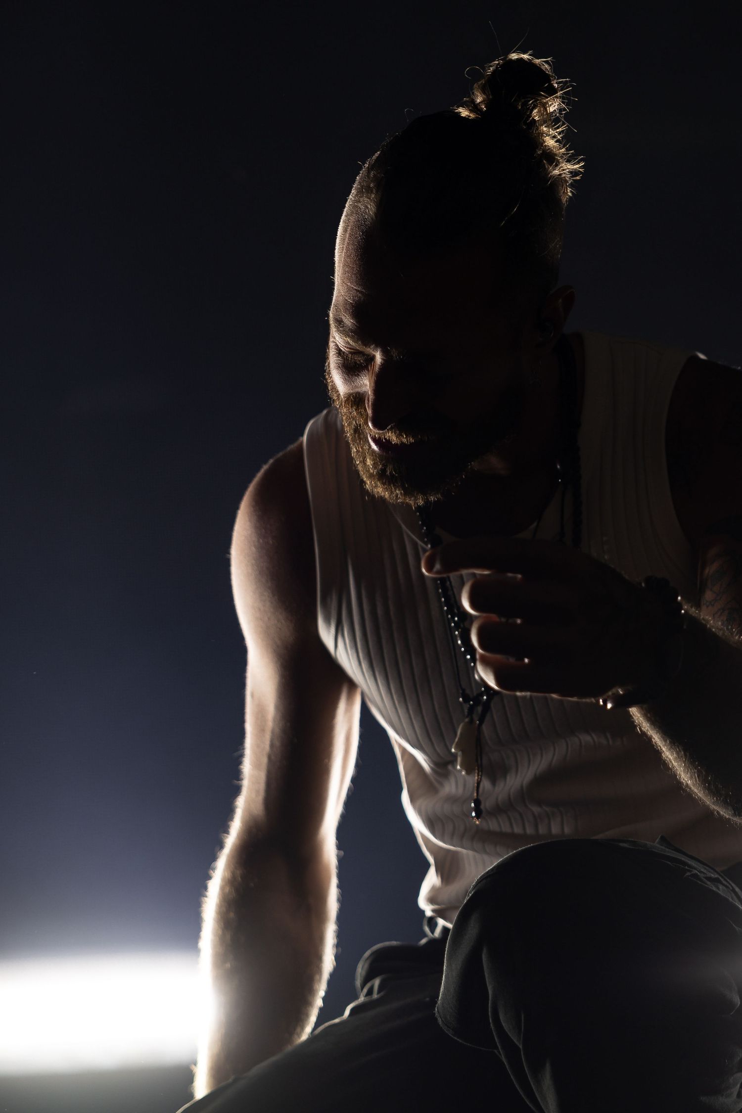A dramatic silhouette sequence shows a person singing into a microphone against bright backlighting.
