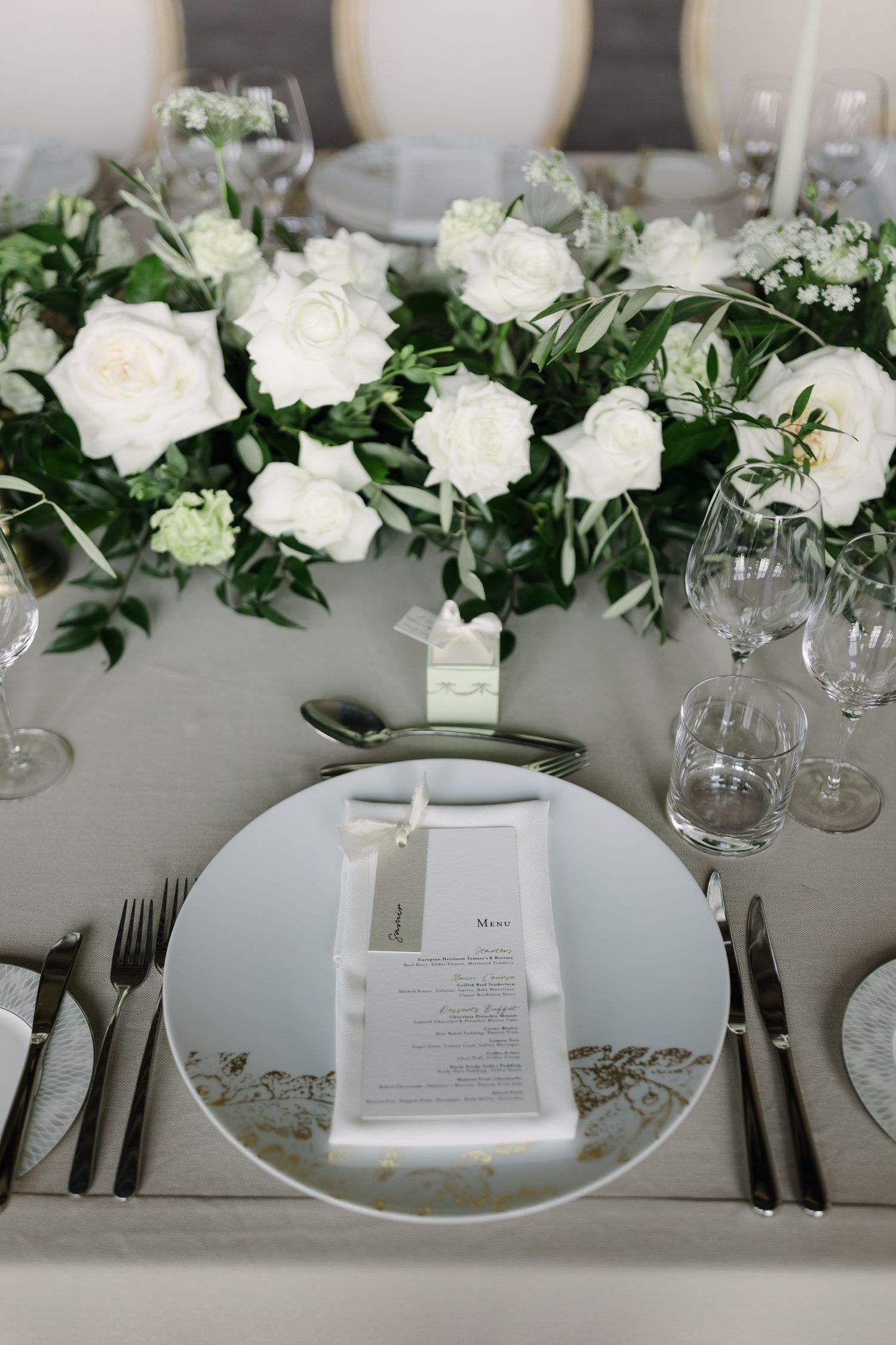 Classic white wedding table setting with floral arrangements and formal place settings.