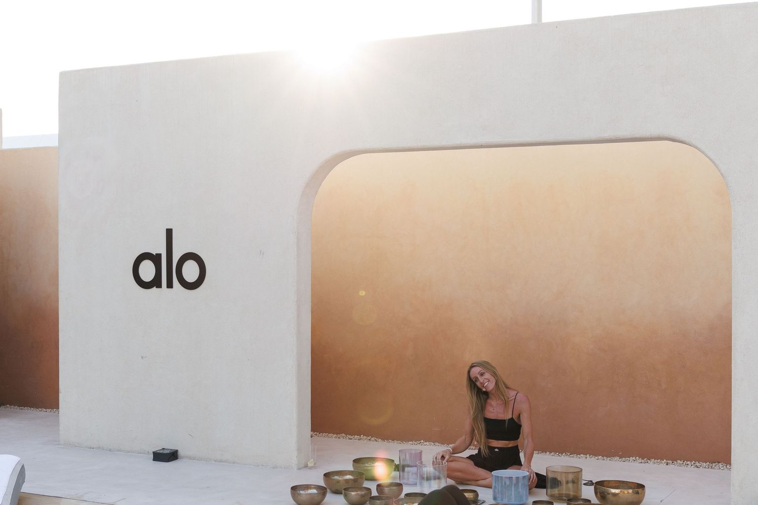 Alo branded wellness space with minimalist white decor and poolside loungers.