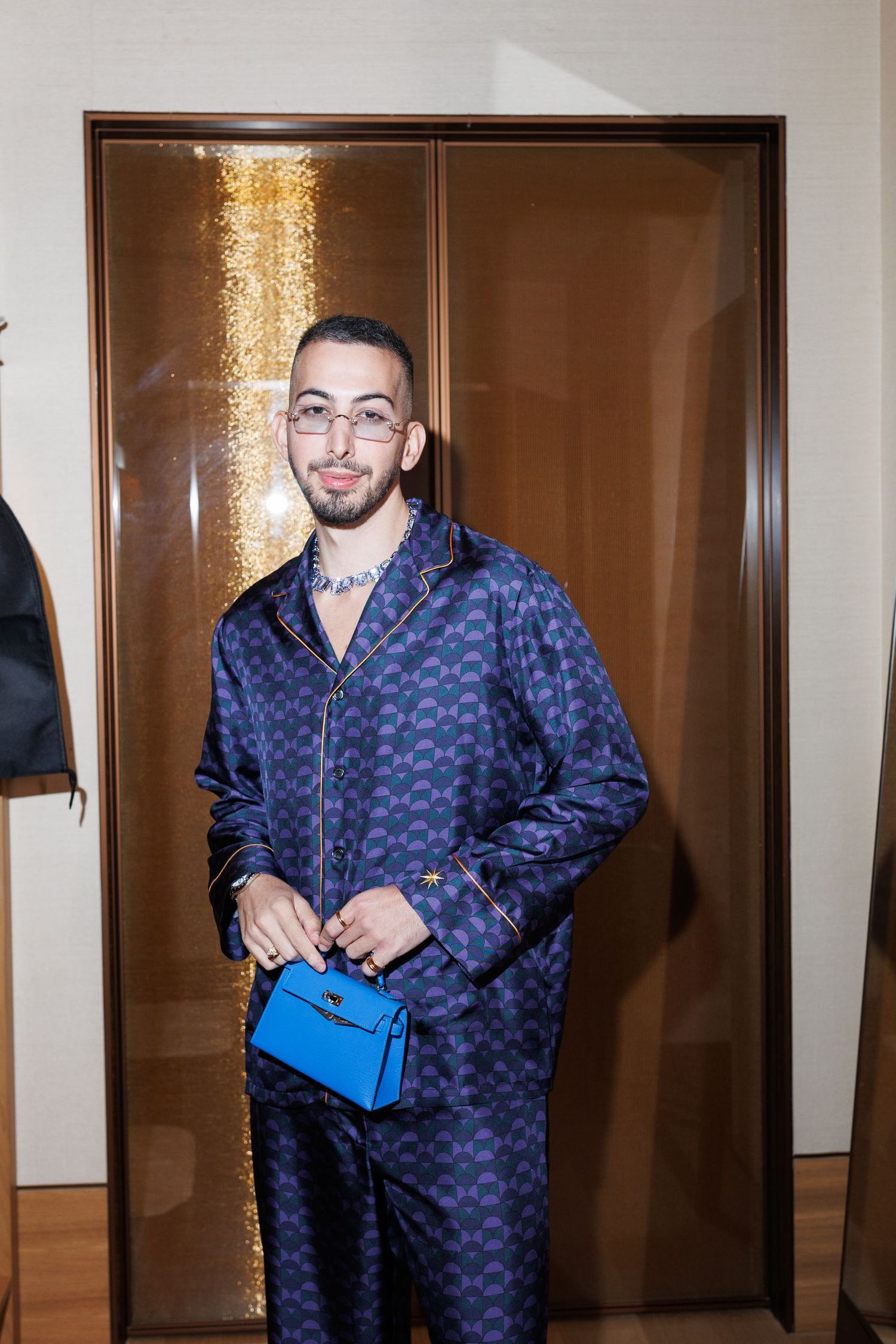 Models wearing matching navy patterned outfits pose in front of wooden doors.