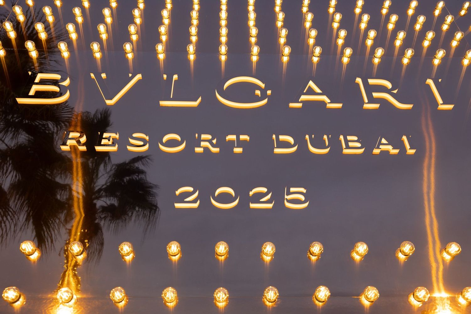 Illuminated Bvlgari Resort Dubai 2023 signage glowing in gold lights at night.