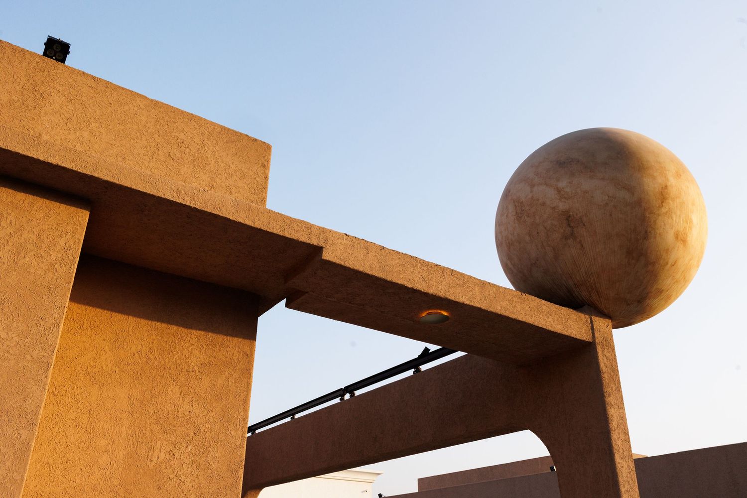 Modern architectural detail of tan concrete walls with geometric shadows at sunset.