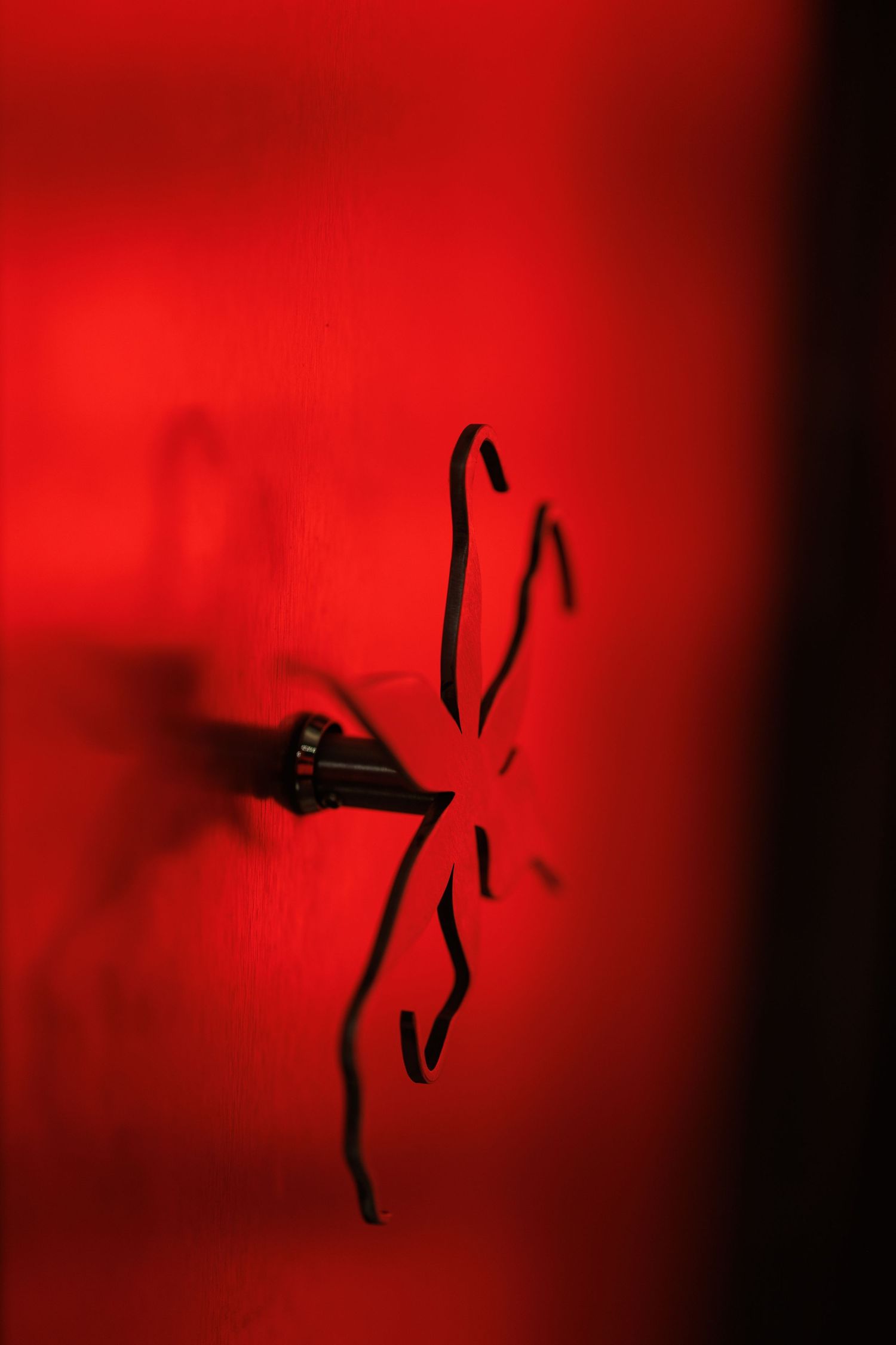 Abstract black shapes against a deep red background creating minimalist art.