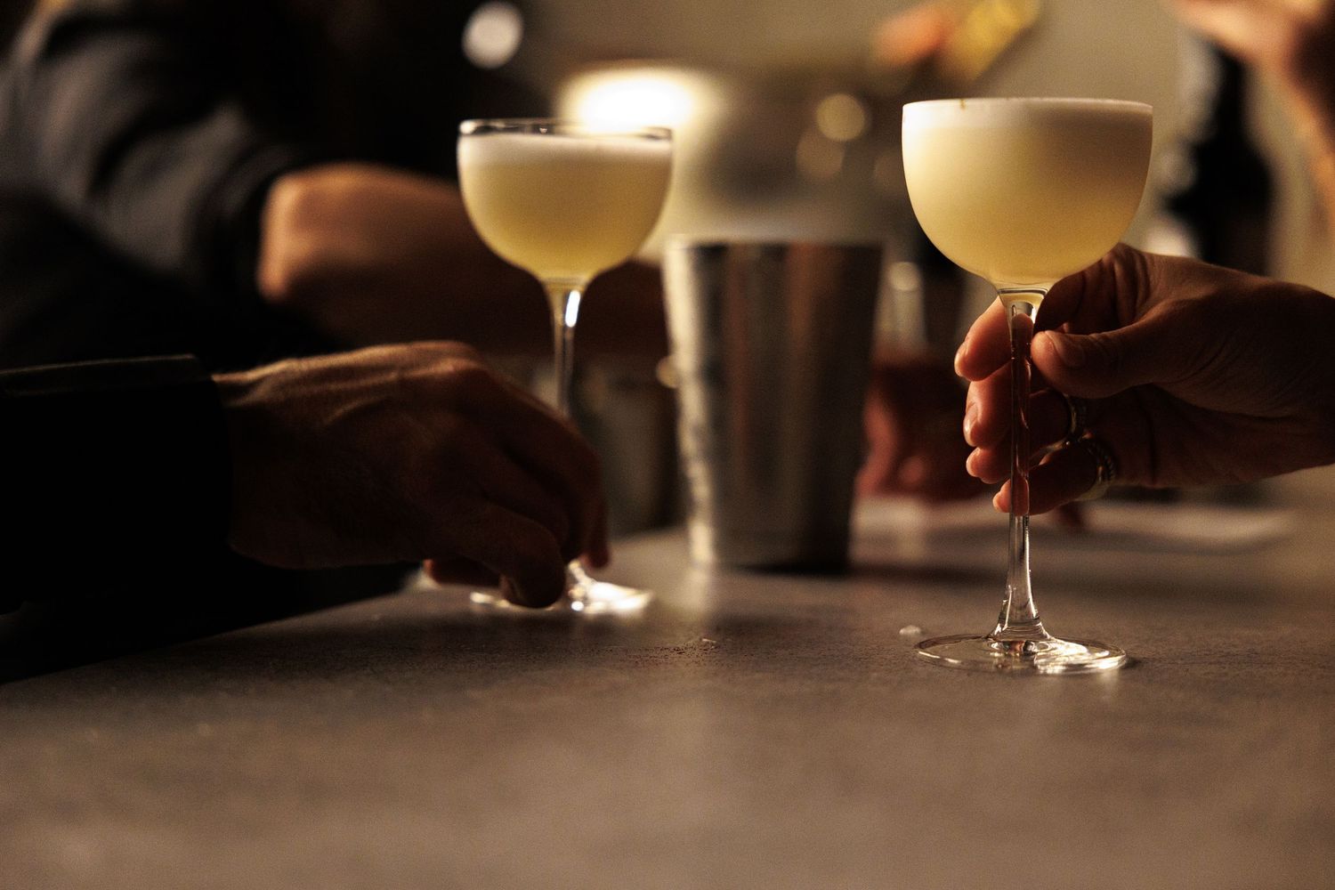 Row of elegant cocktail glasses filled with creamy drinks on a dark bar counter.