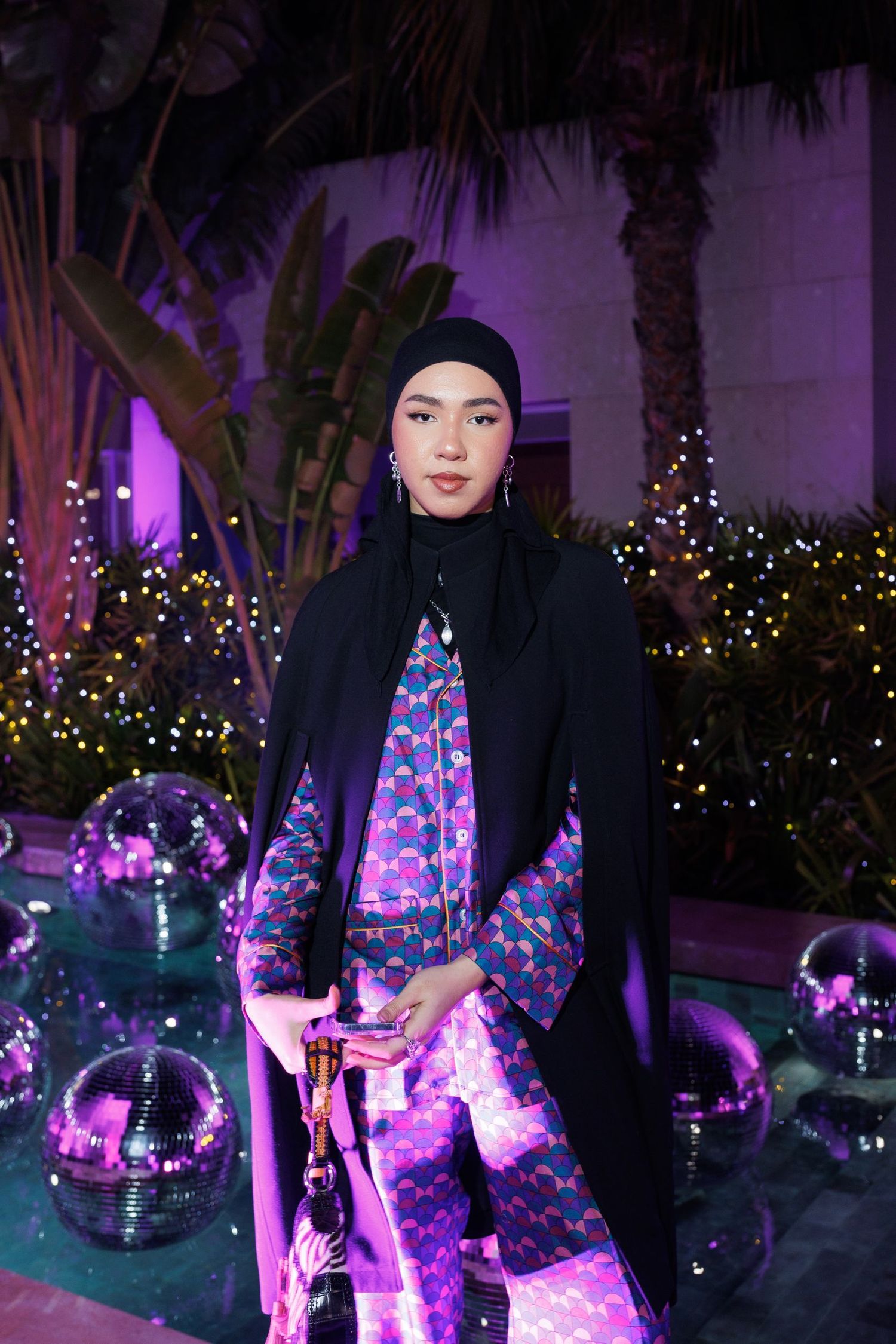 Nighttime party scene with illuminated decorations and palm trees in purple lighting.
