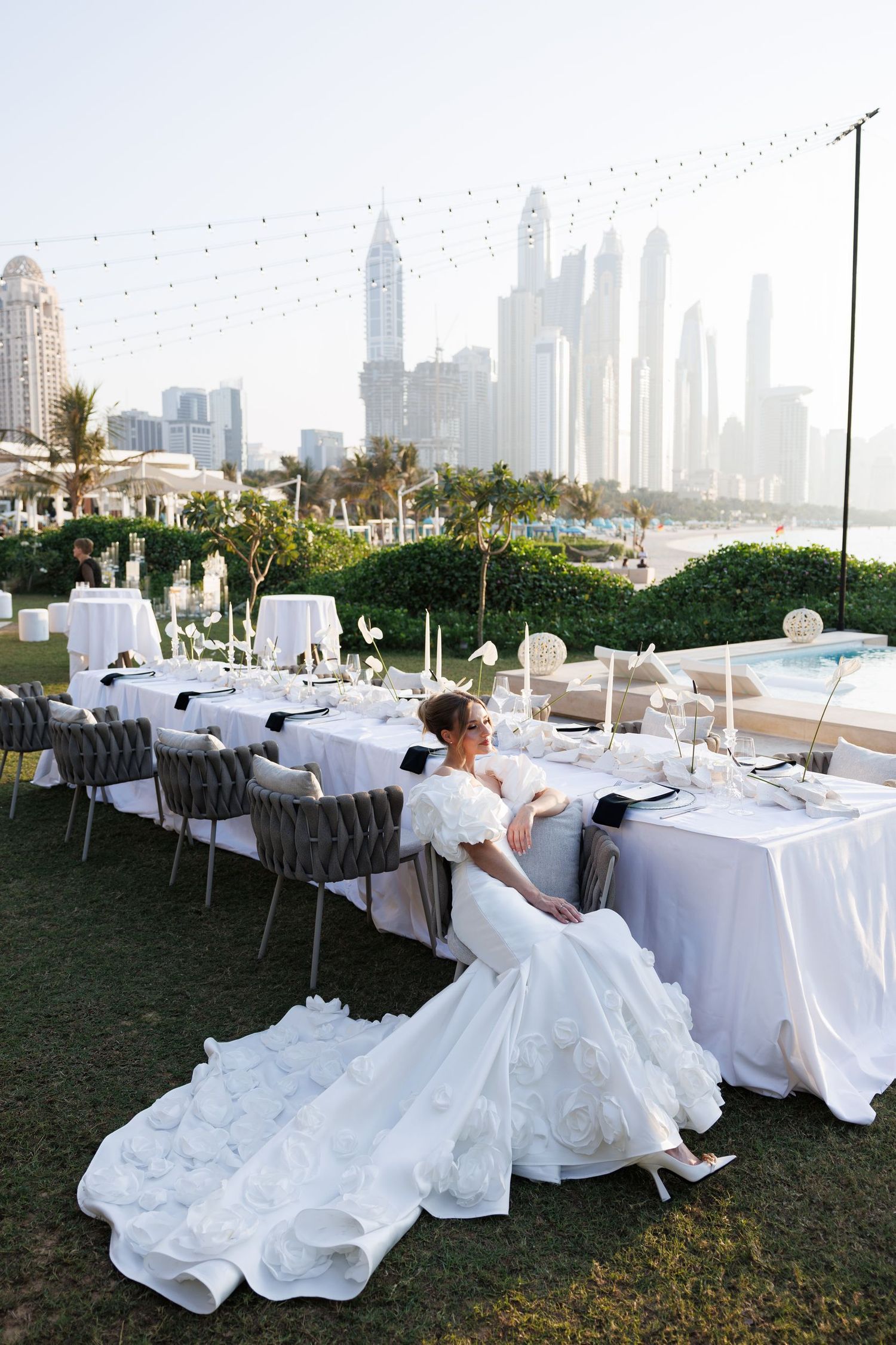 Elegant wedding reception setup with white tablecloths and Dubai skyline in the background.