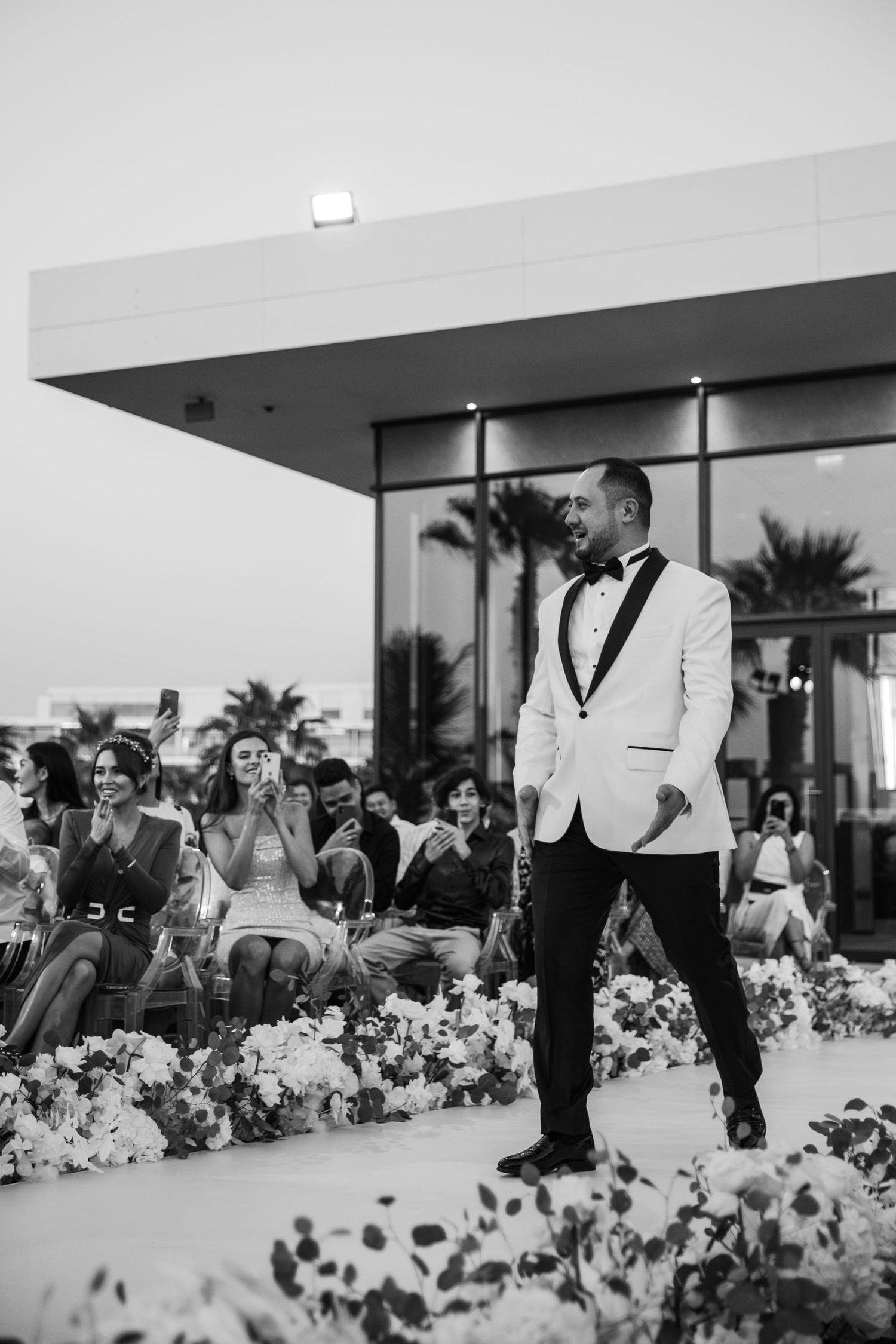 Wedding guests react emotionally during an outdoor ceremony with floral decorations.