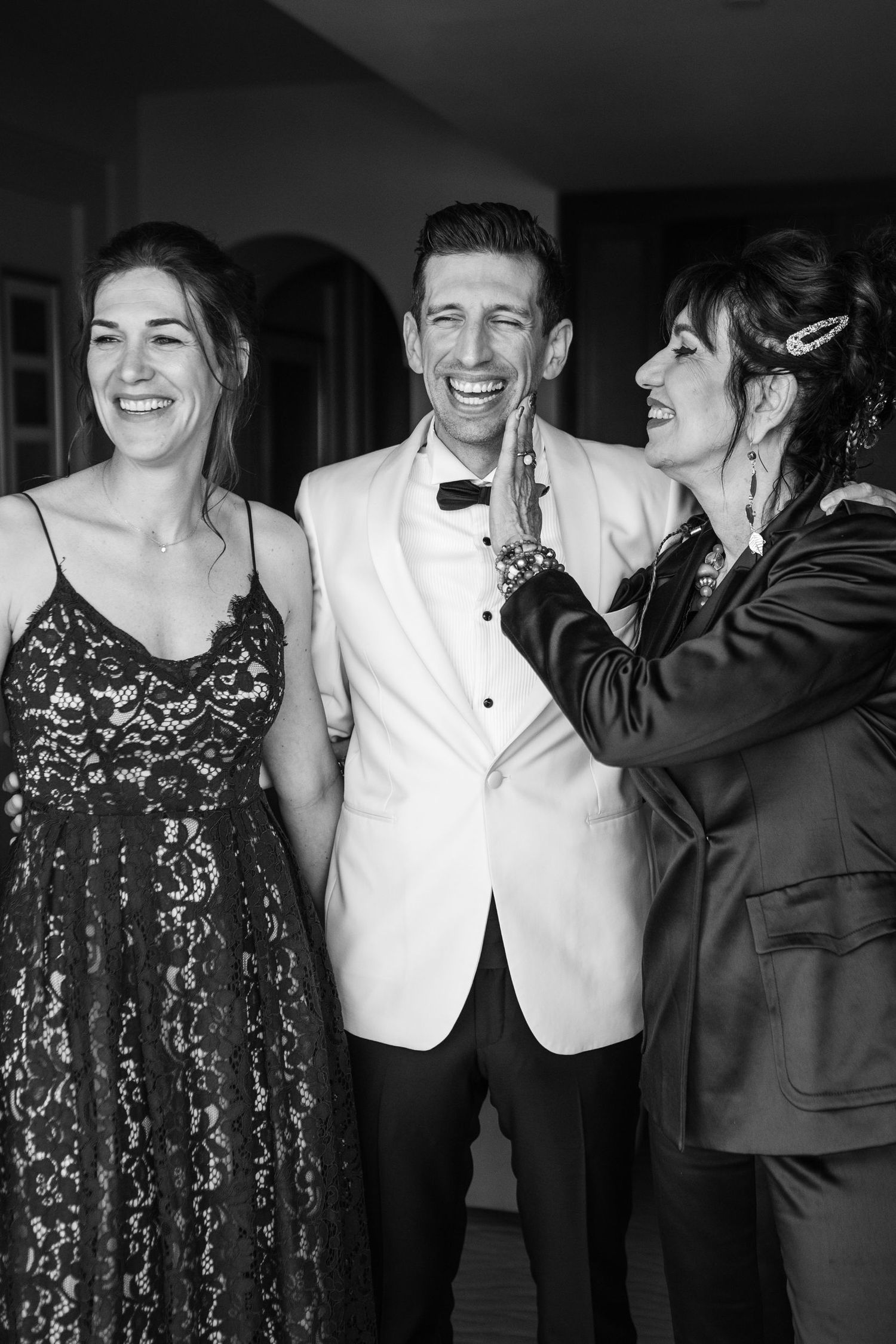 Three people sharing a candid laughing moment at a formal event.