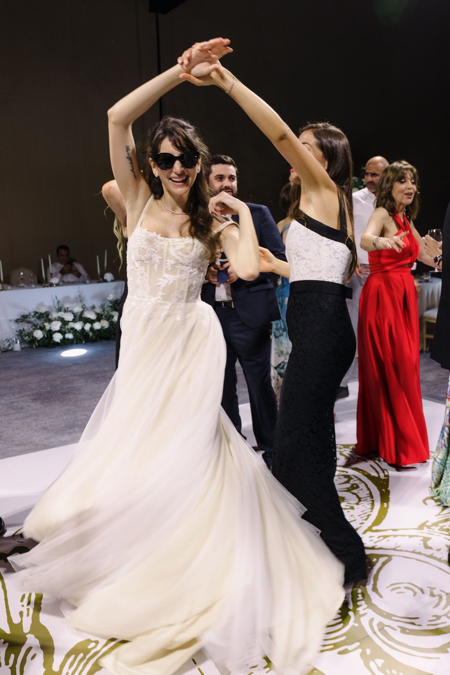 Wedding guests dancing and celebrating on the dance floor with a bride in a flowing white gown.