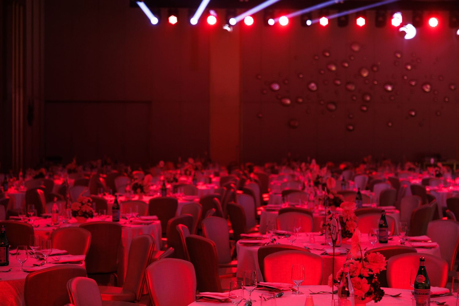 Banquet hall setup with tables under dramatic red lighting effects.