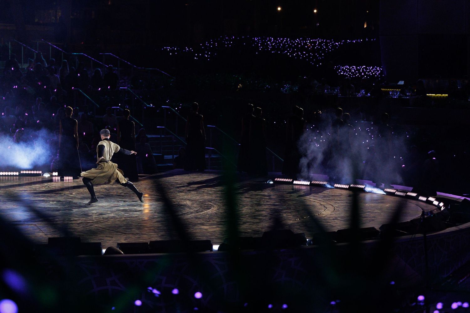 Figure skaters perform an elegant routine on illuminated ice during a nighttime show.