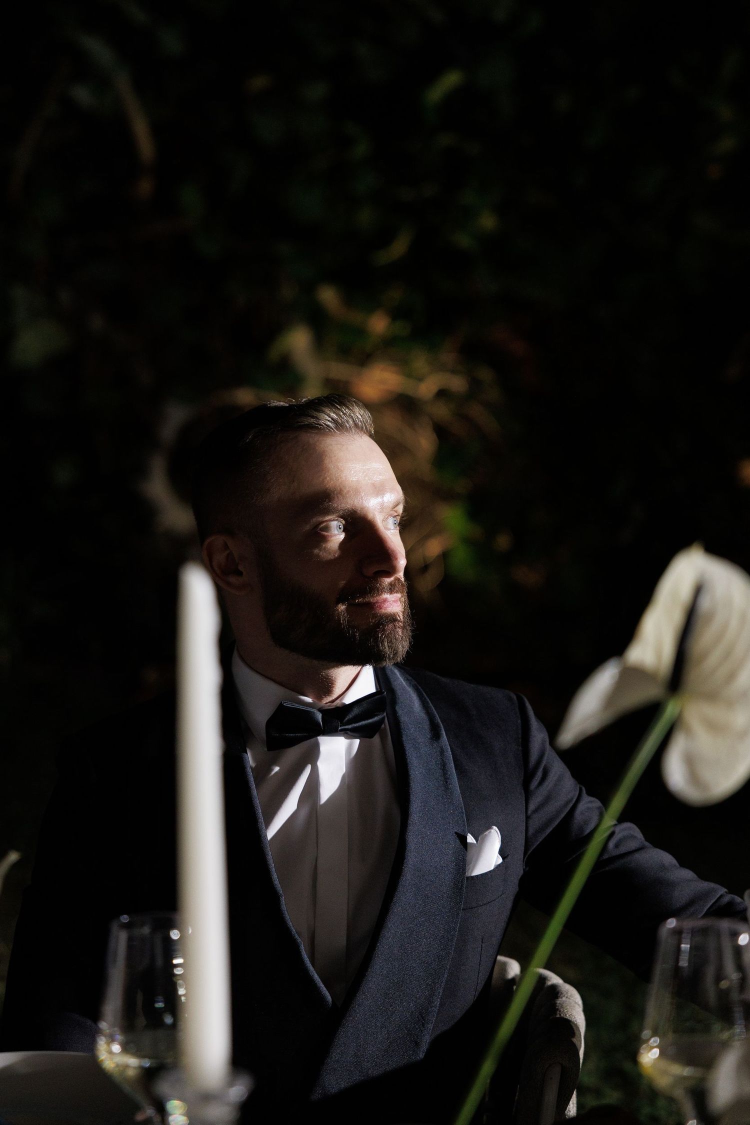 Dramatic lighting creates silhouette of person in formal attire at evening event.