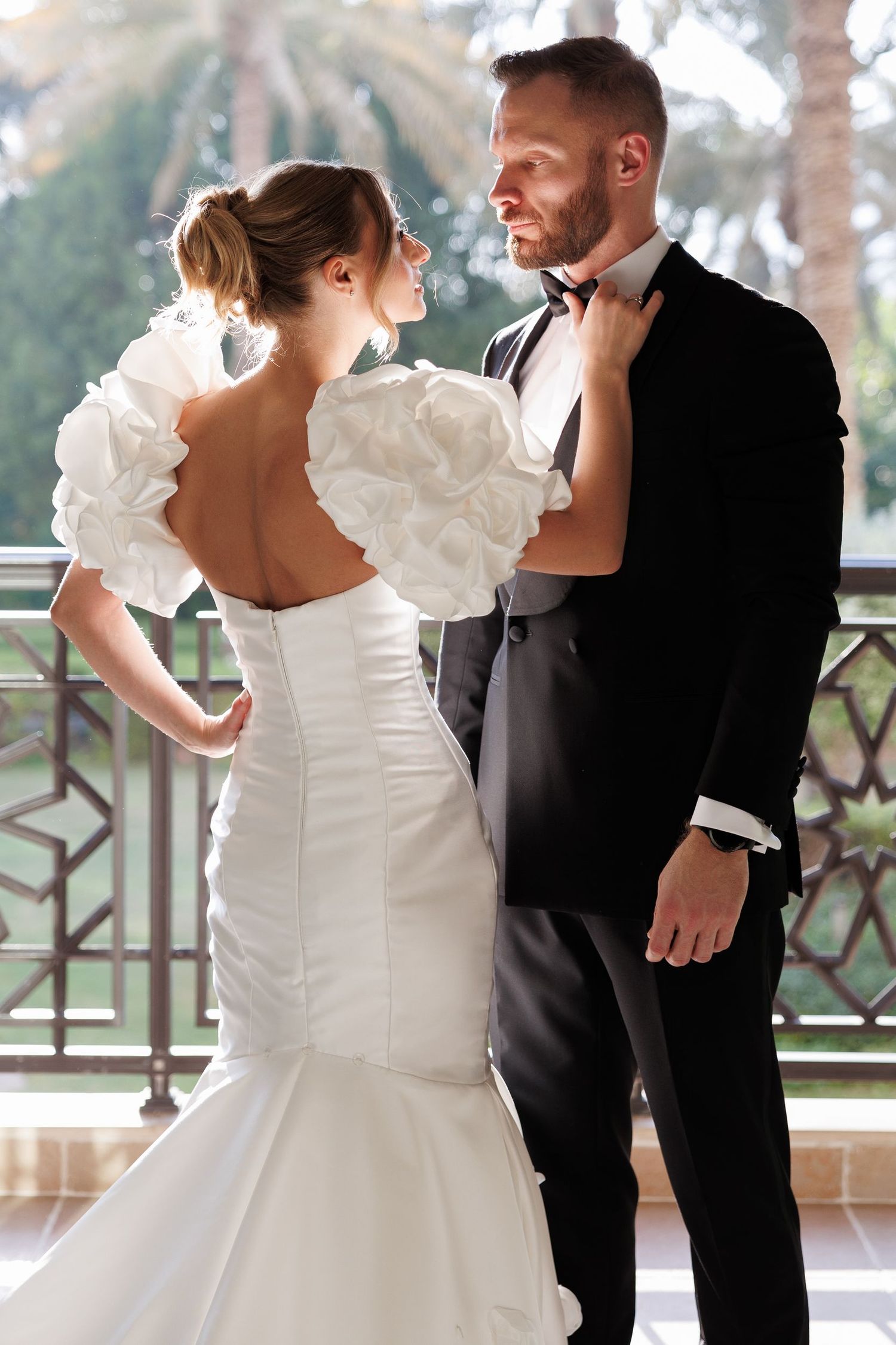 Elegant wedding dance sequence on balcony with palm trees.