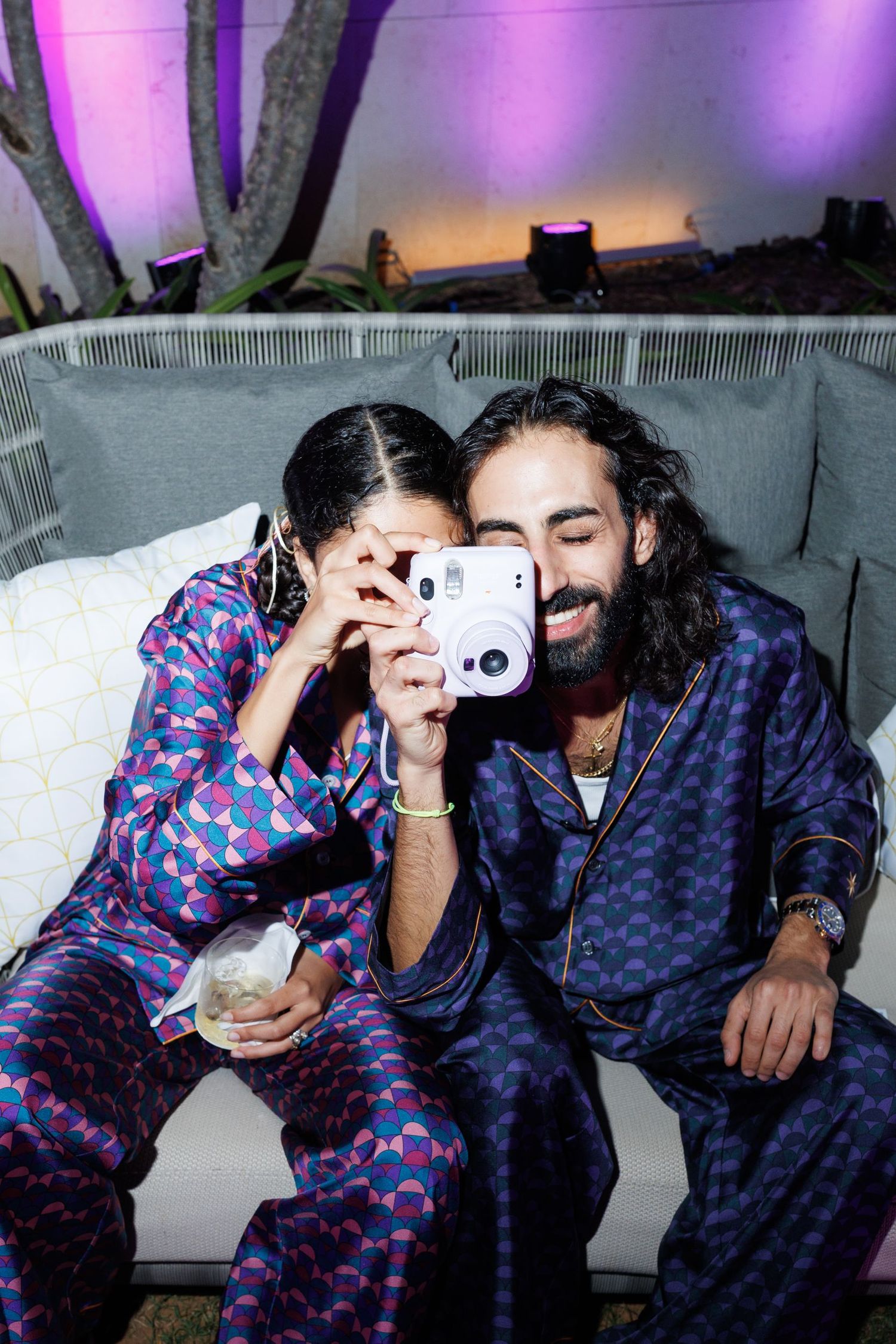 Couple in matching patterned pajamas sharing intimate moments on a couch.