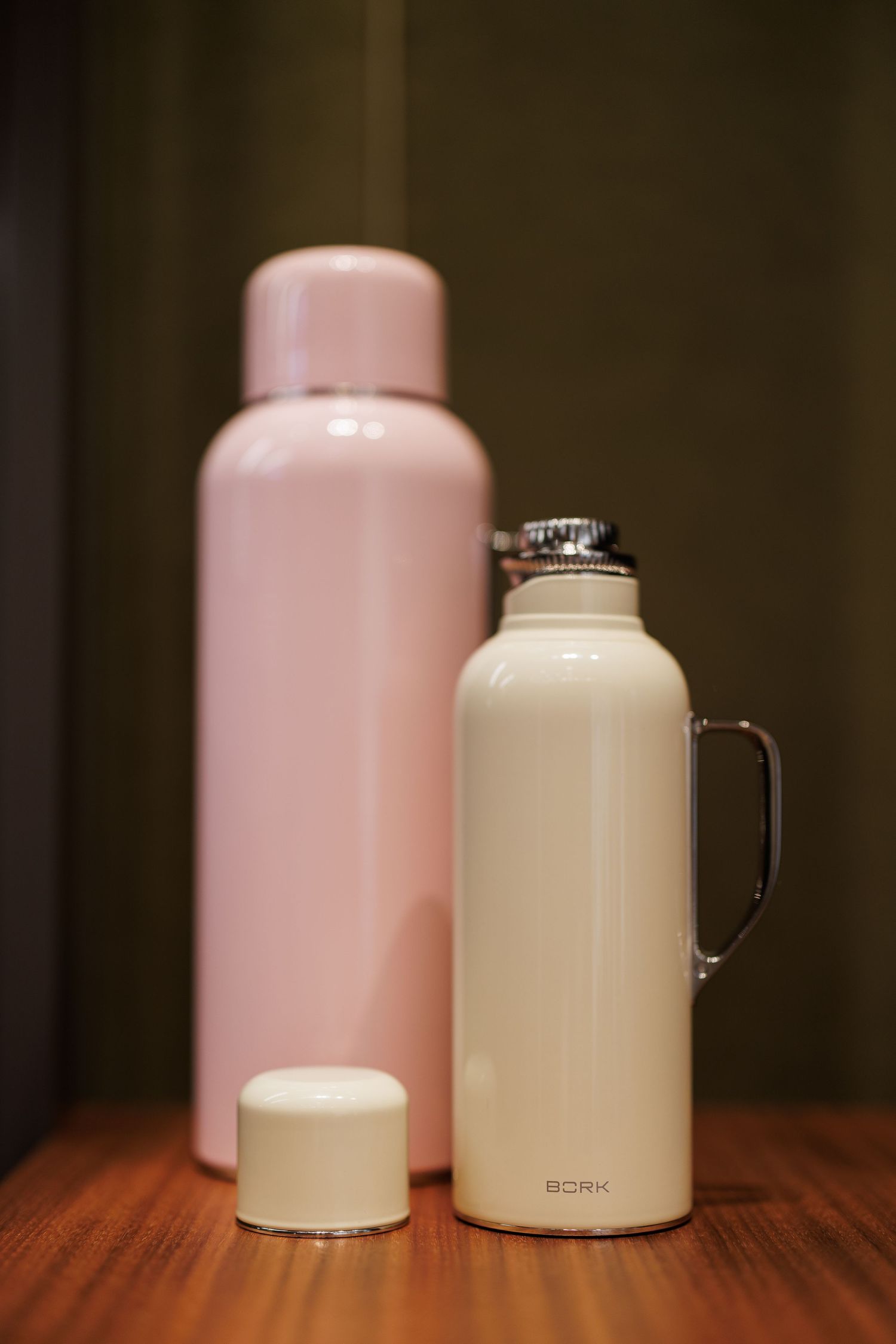 White and beige thermal drink containers arranged on a wooden surface.