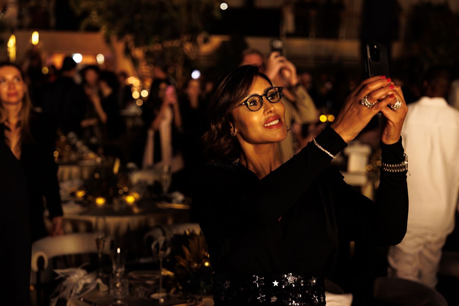 People dancing and celebrating at a dimly lit nightclub or party venue with festive lighting and atmosphere.